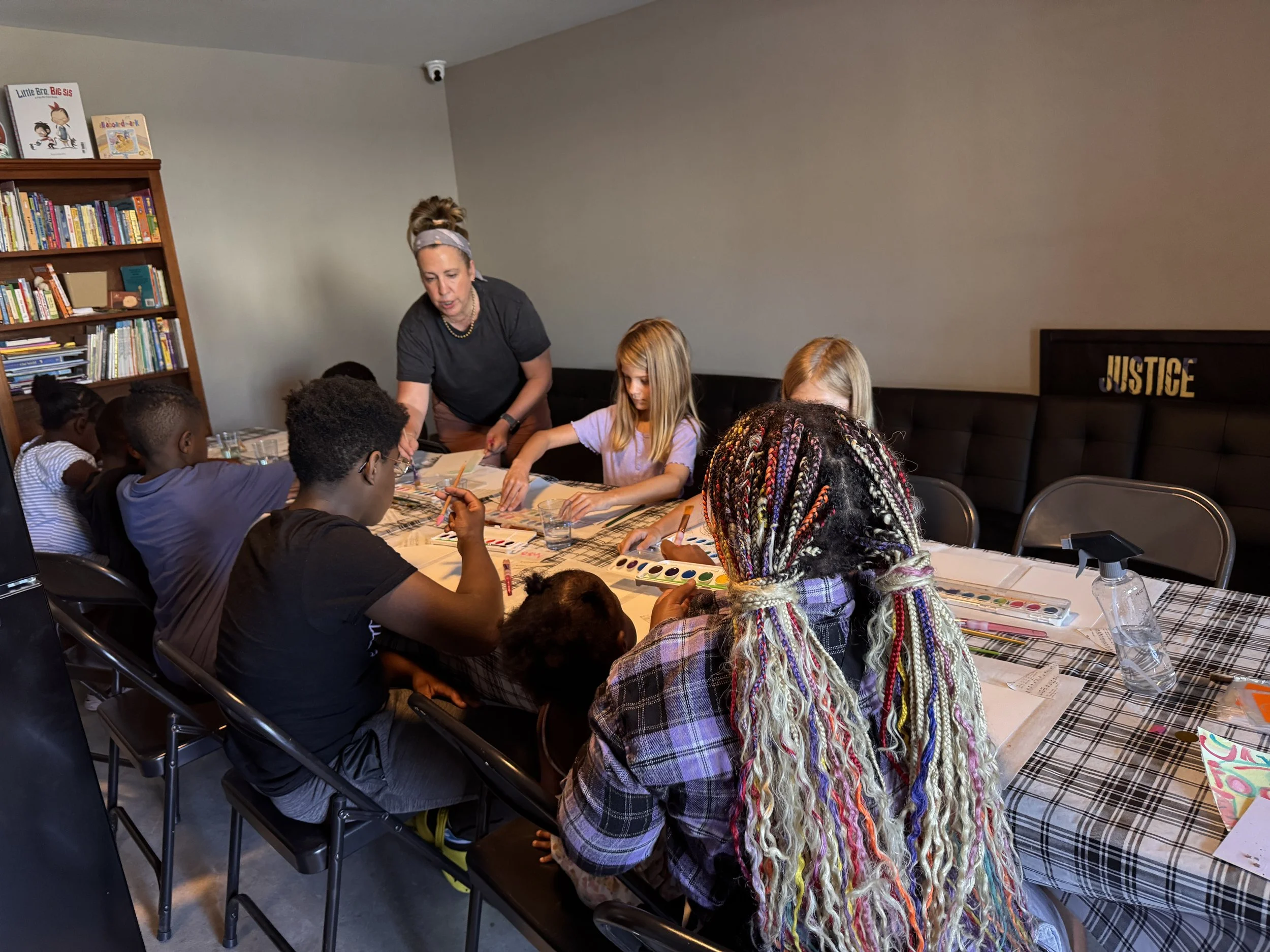 woman teaches young kid art at table