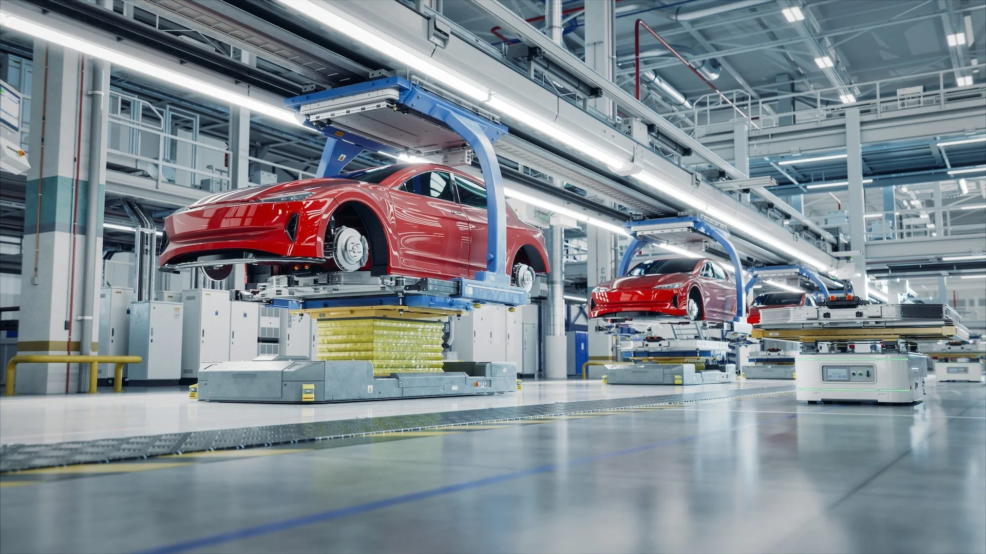 Inside a factory automation line, red car bodies are being assembled on robotic platforms.