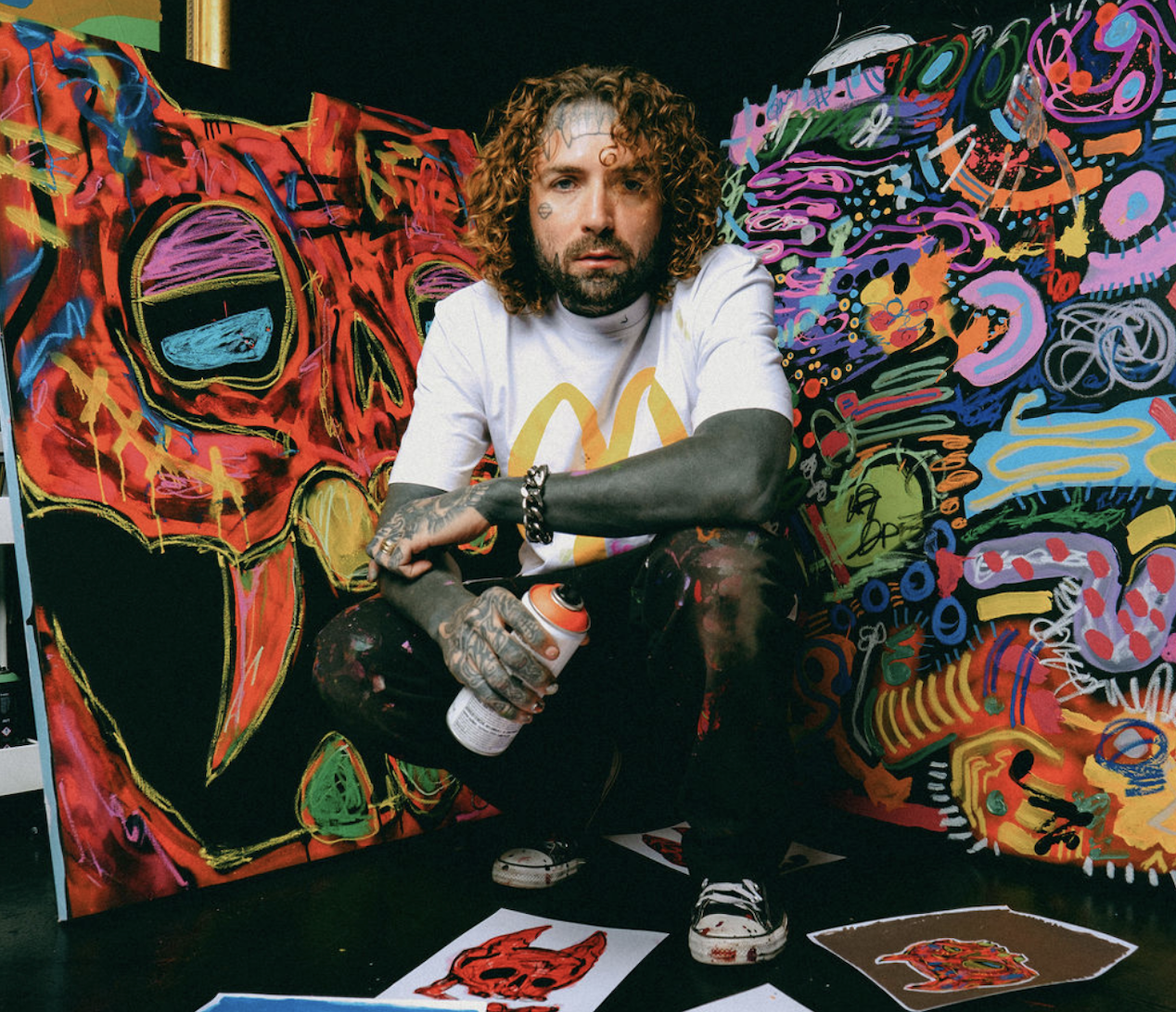 Caskey in his art studio working on unique signature pieces. He is wearing a McDonald's Tshirt holding spray paint cans. Shot during an intimate photoshoot.