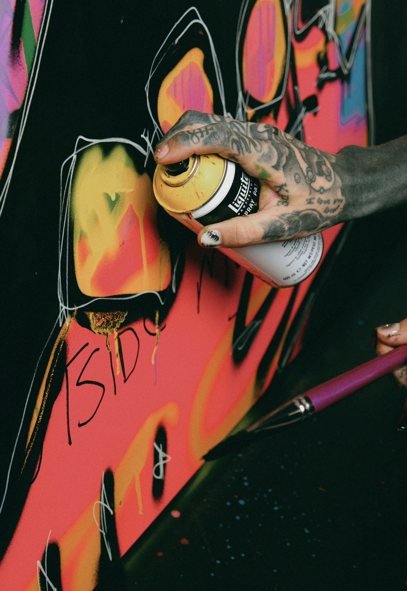 Caskey spray-painting the word FREEDOM across a colorful mixed-media canvas.