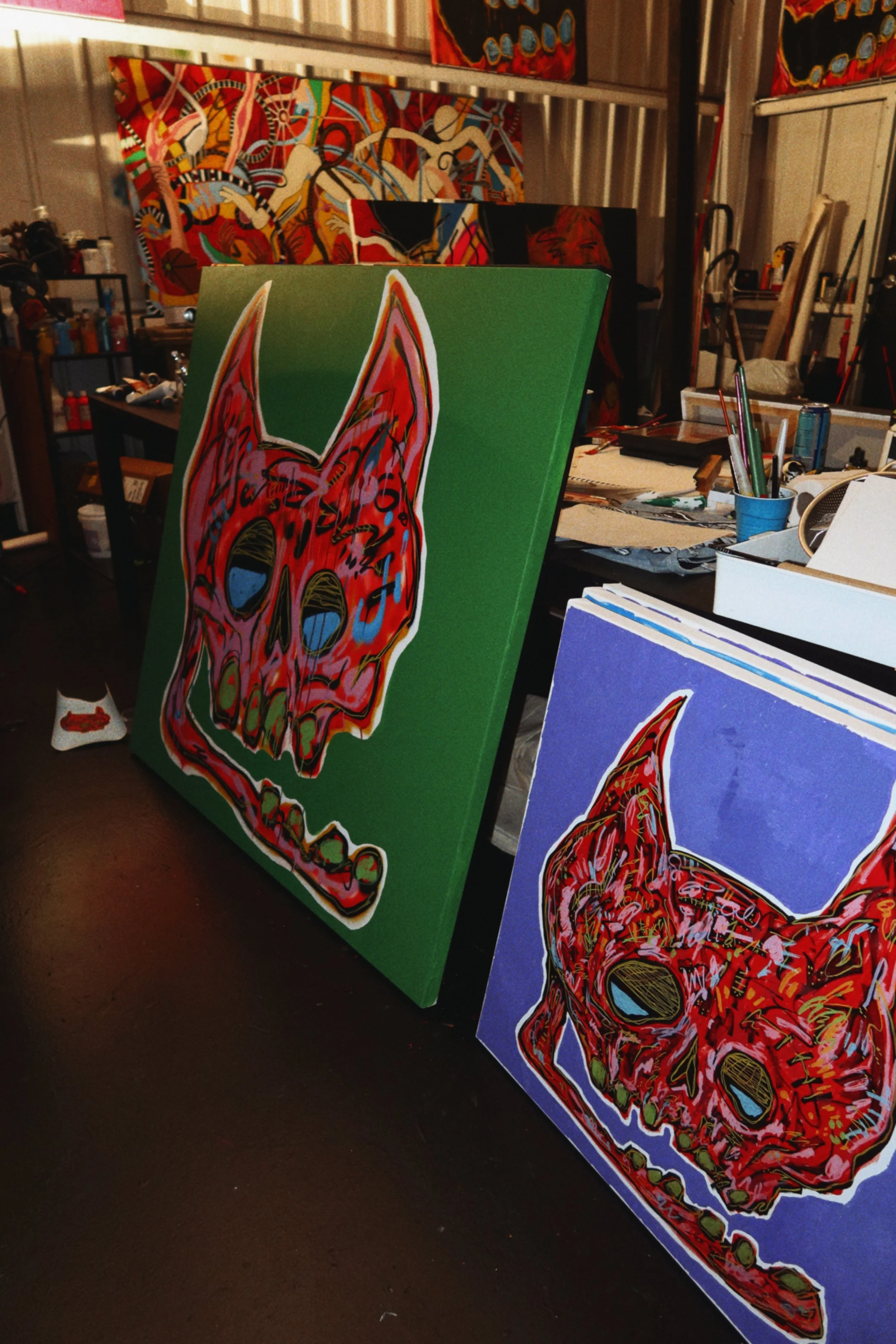 Colorful original Caskey paintings featuring skulls and abstract figures arranged throughout his working art studio.