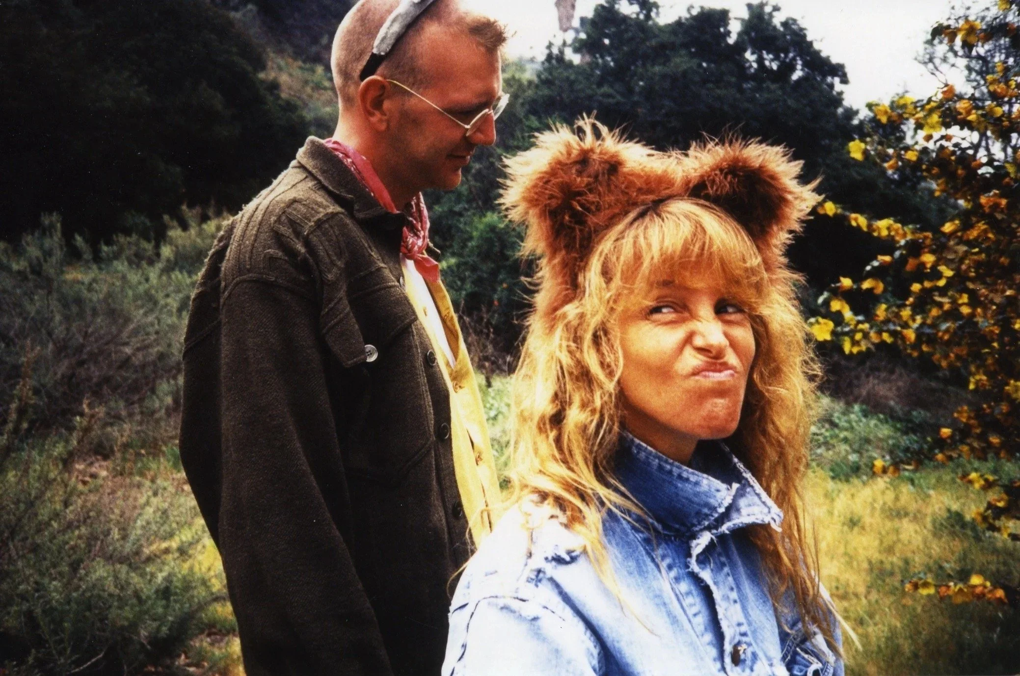 A man looking down at a young girl wearing a lion costume with a forest background.