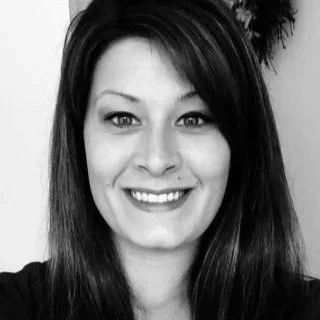 Black and white portrait of a smiling woman with straight hair and bright eyes.