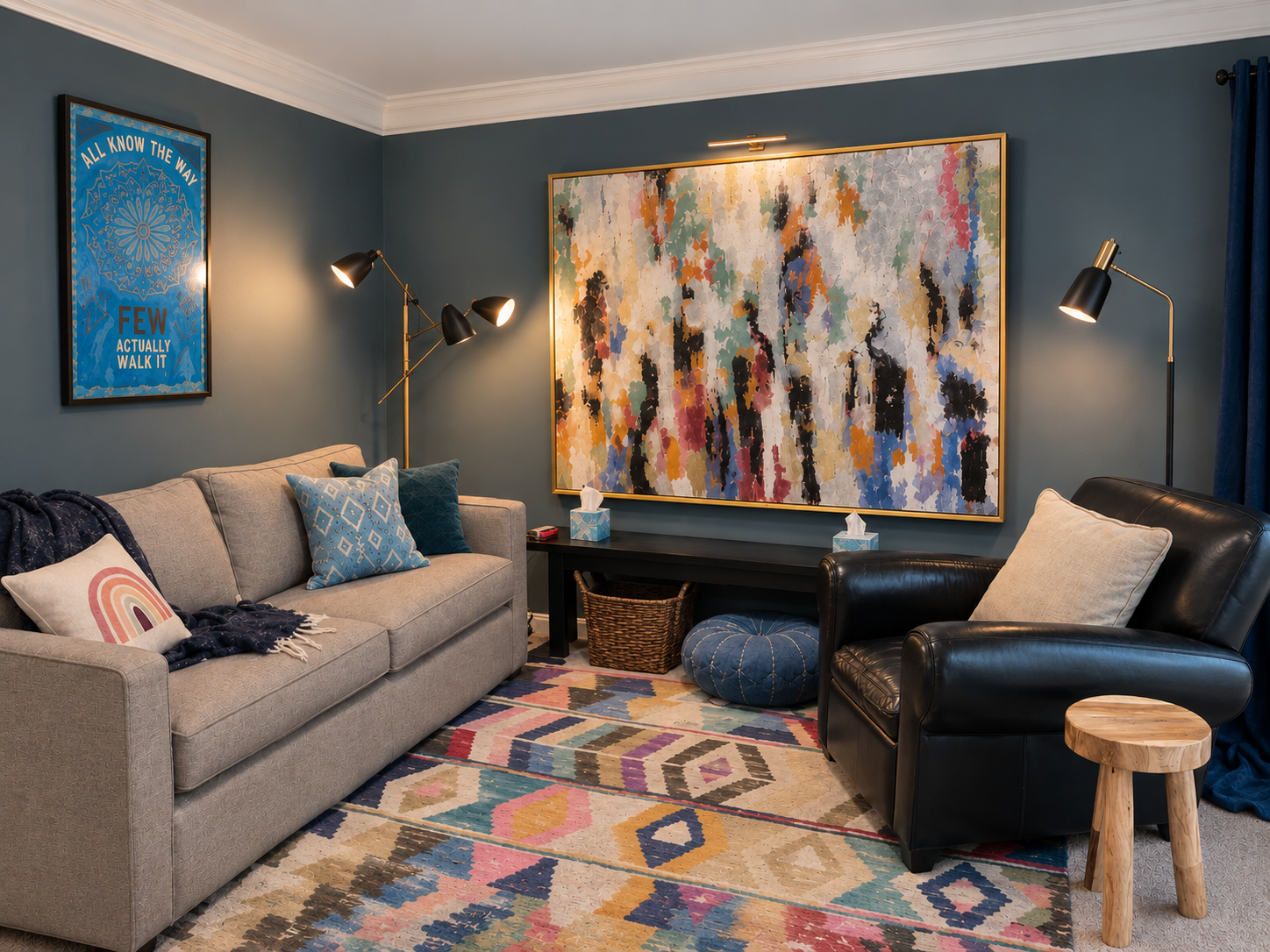 Living room with a beige sofa decorated with blue and rainbow pillows, a black leather armchair with a beige pillow, a wooden stool, a colorful patterned rug, and an abstract painting on the wall. There are two modern floor lamps and a framed quote poster on the teal walls.