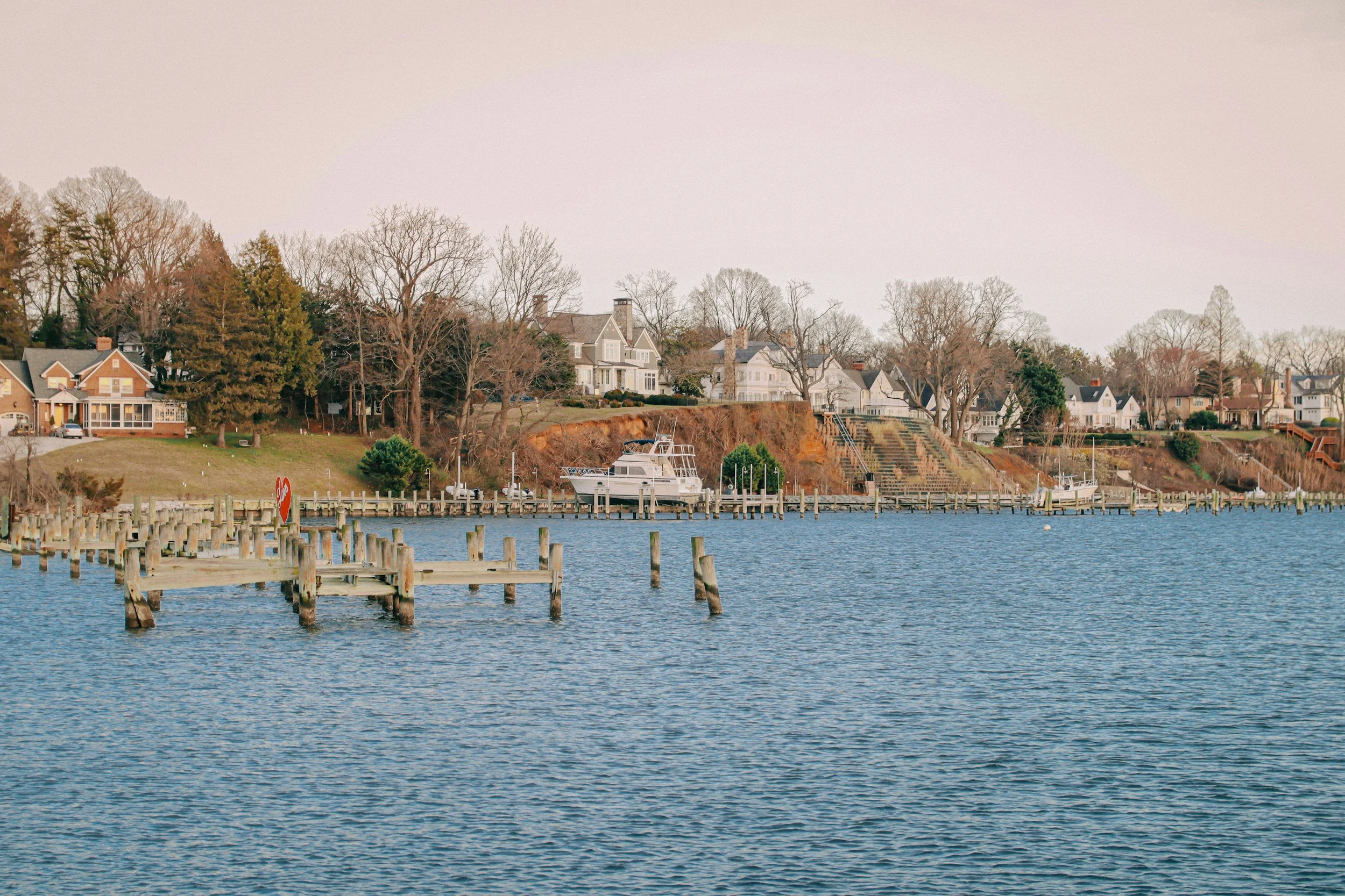 Waterfront with houses on a hill, trees, dock, and boats