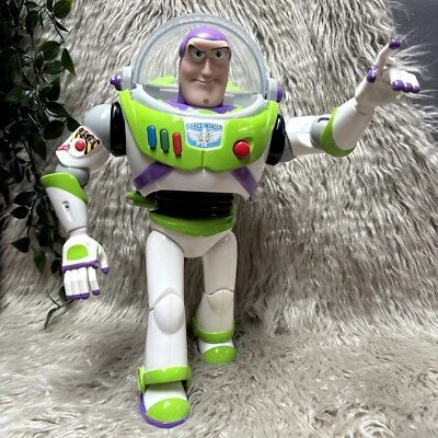 Toy figure of Buzz Lightyear from Toy Story standing on a textured surface with a furry background and a plant on the side.