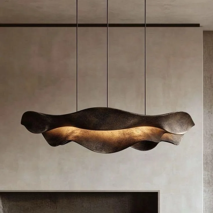 A modern suspended ceiling light fixture with an abstract, organic shape in dark and metallic tones hanging from the ceiling.