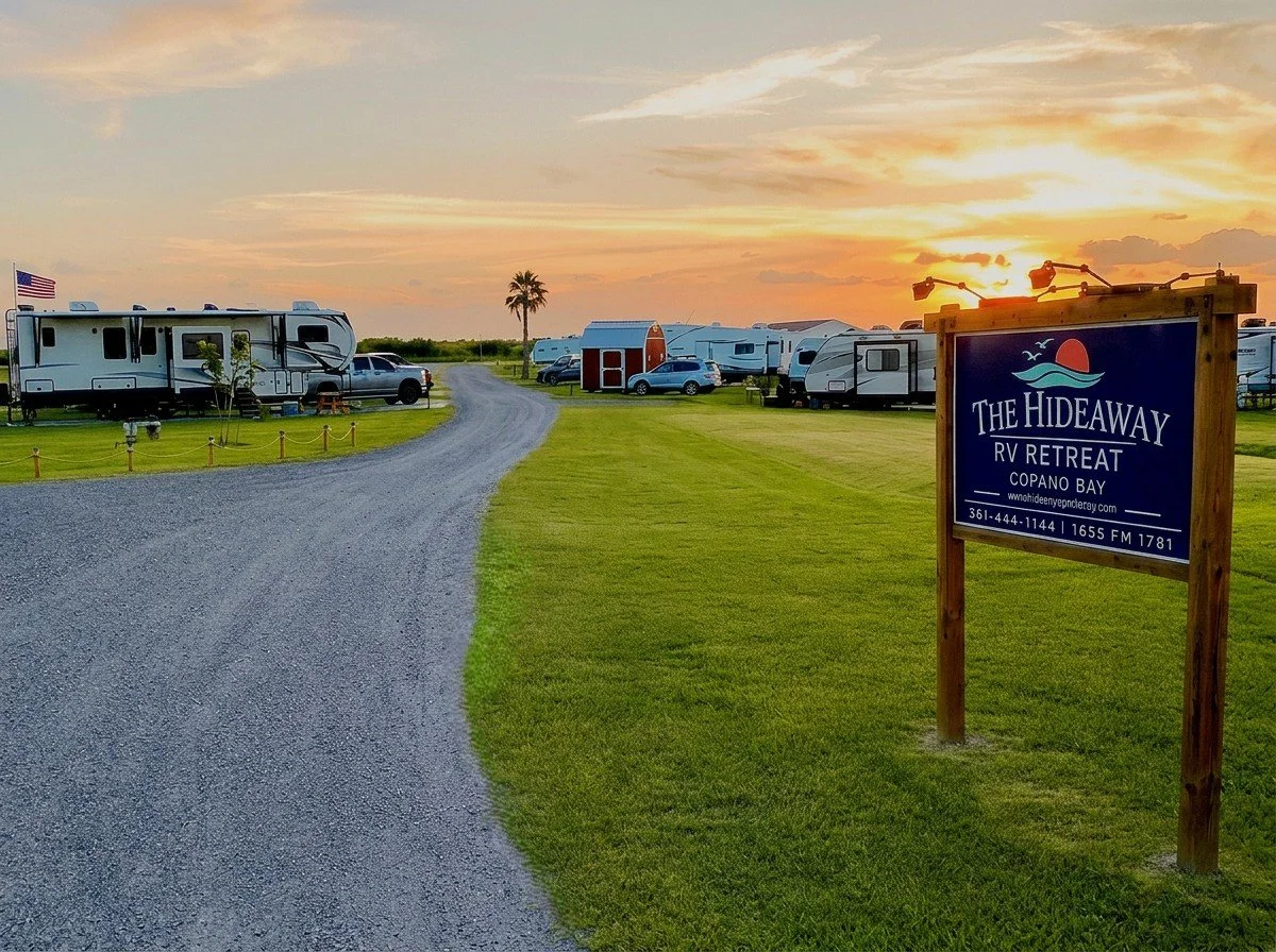 RVs set up on well-maintained grounds at The Hideaway RV Retreat in Rockport, Texas, beneath a colorful coastal sunset.