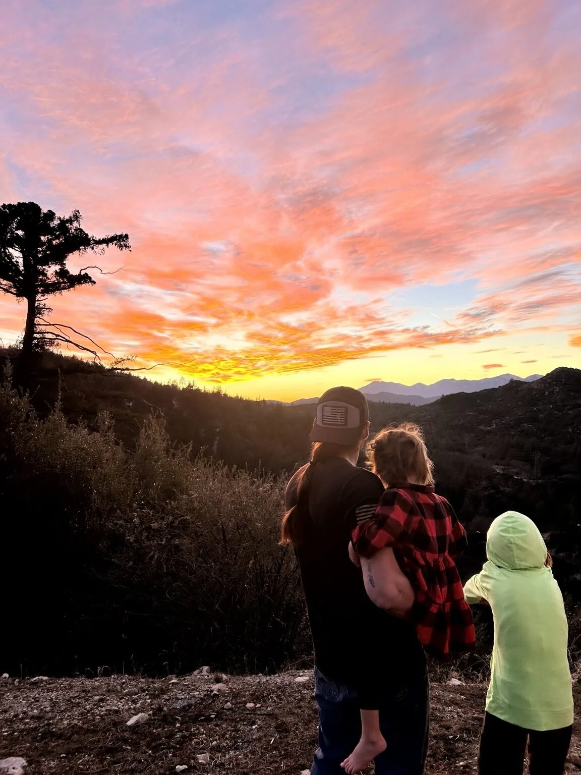 Cody Gomez with his children overlooking the mountain community at sunset