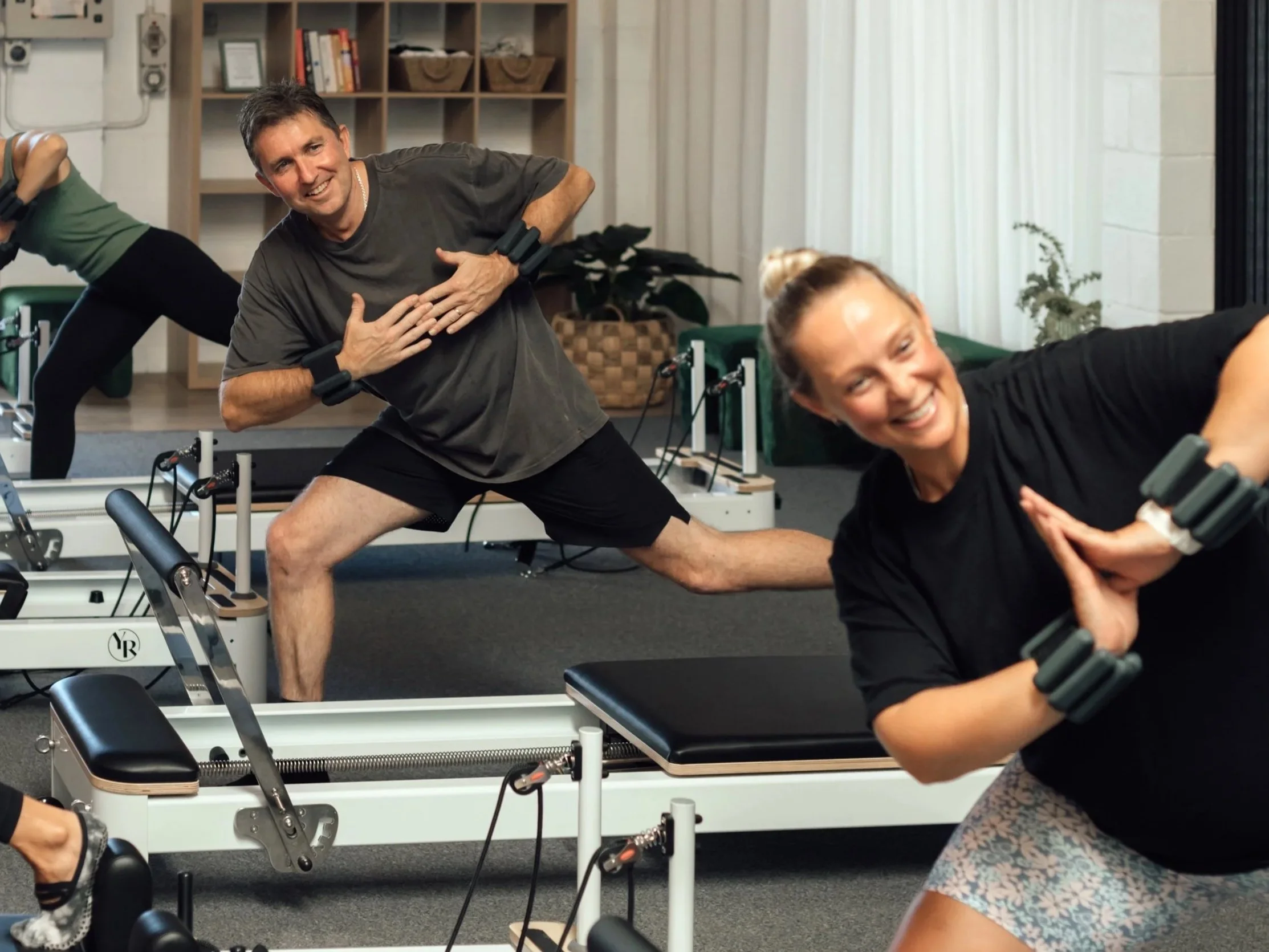 A male and female client of Mindful Movement Studio in a lunge exercise on the Reformer.