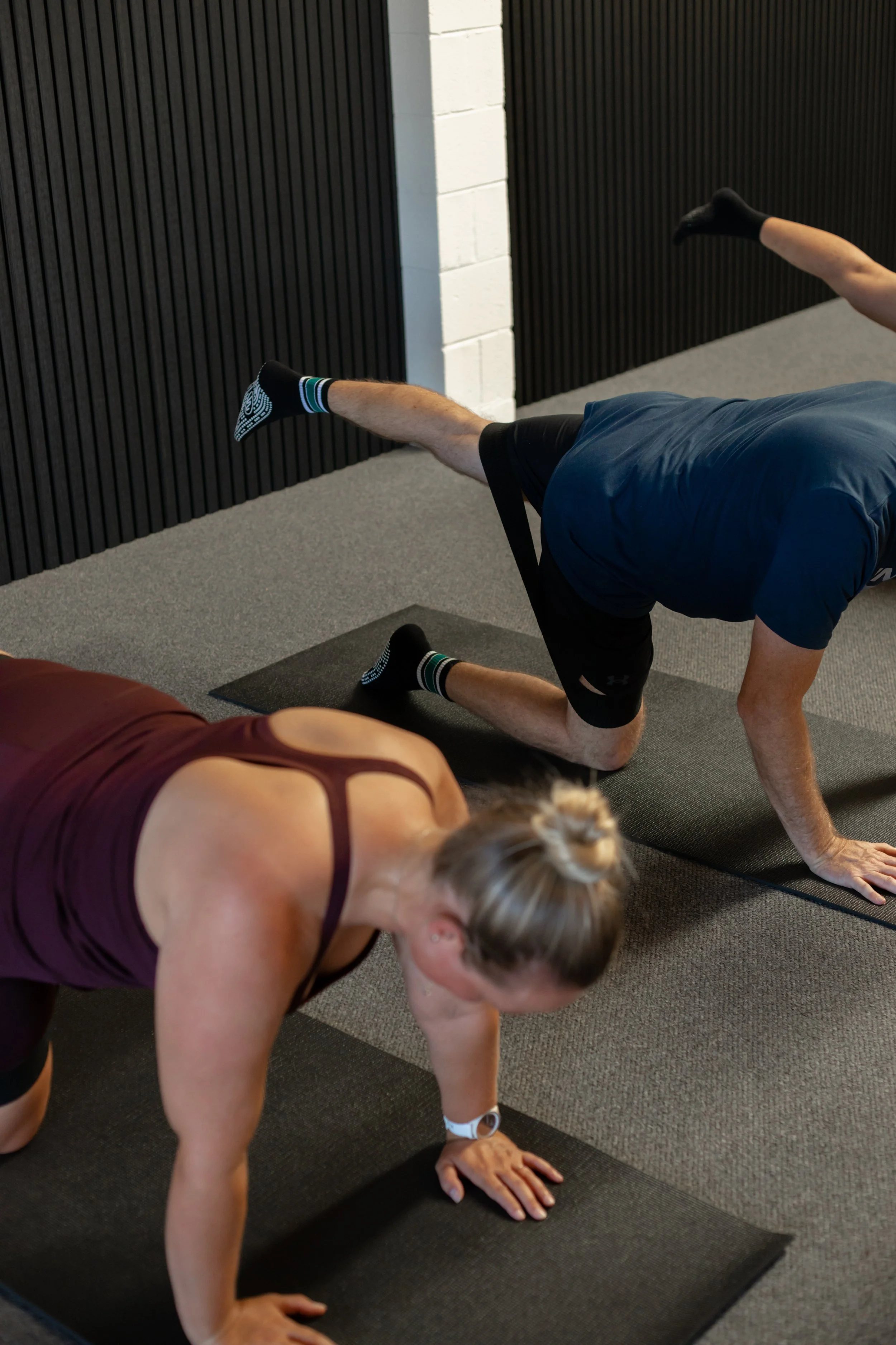 A male and female client in a Mat Pilates class