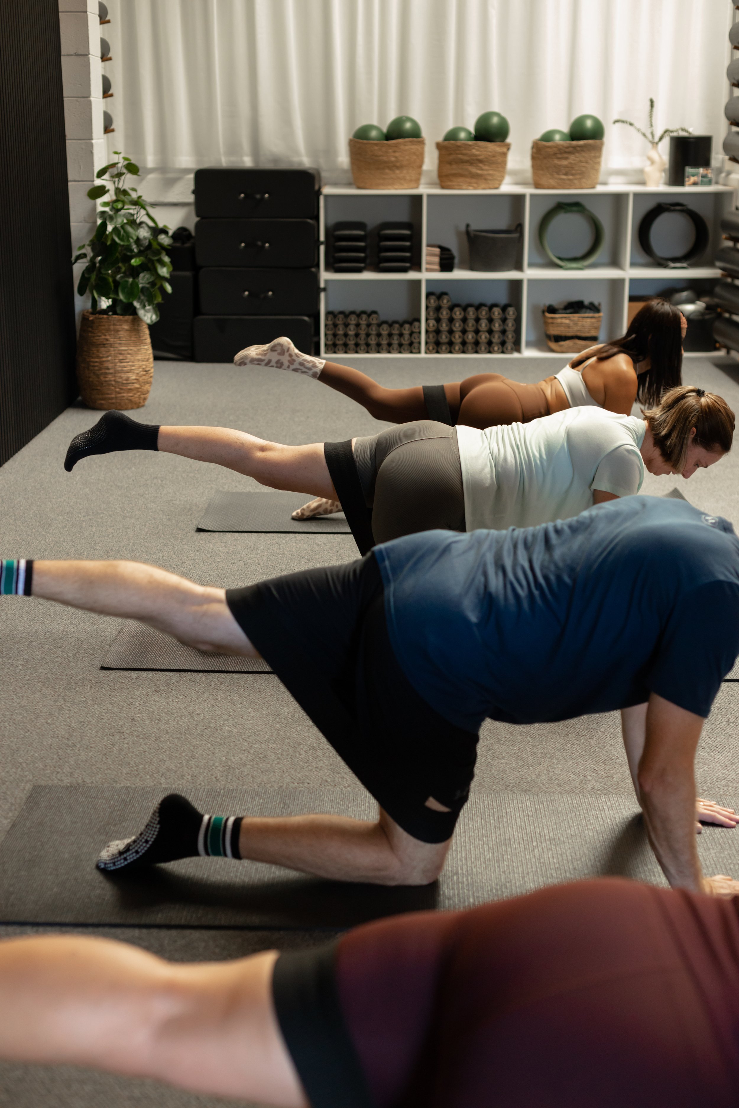 Multiple clients in a Mat Pilates class, using a loop band for a Glute exercise.