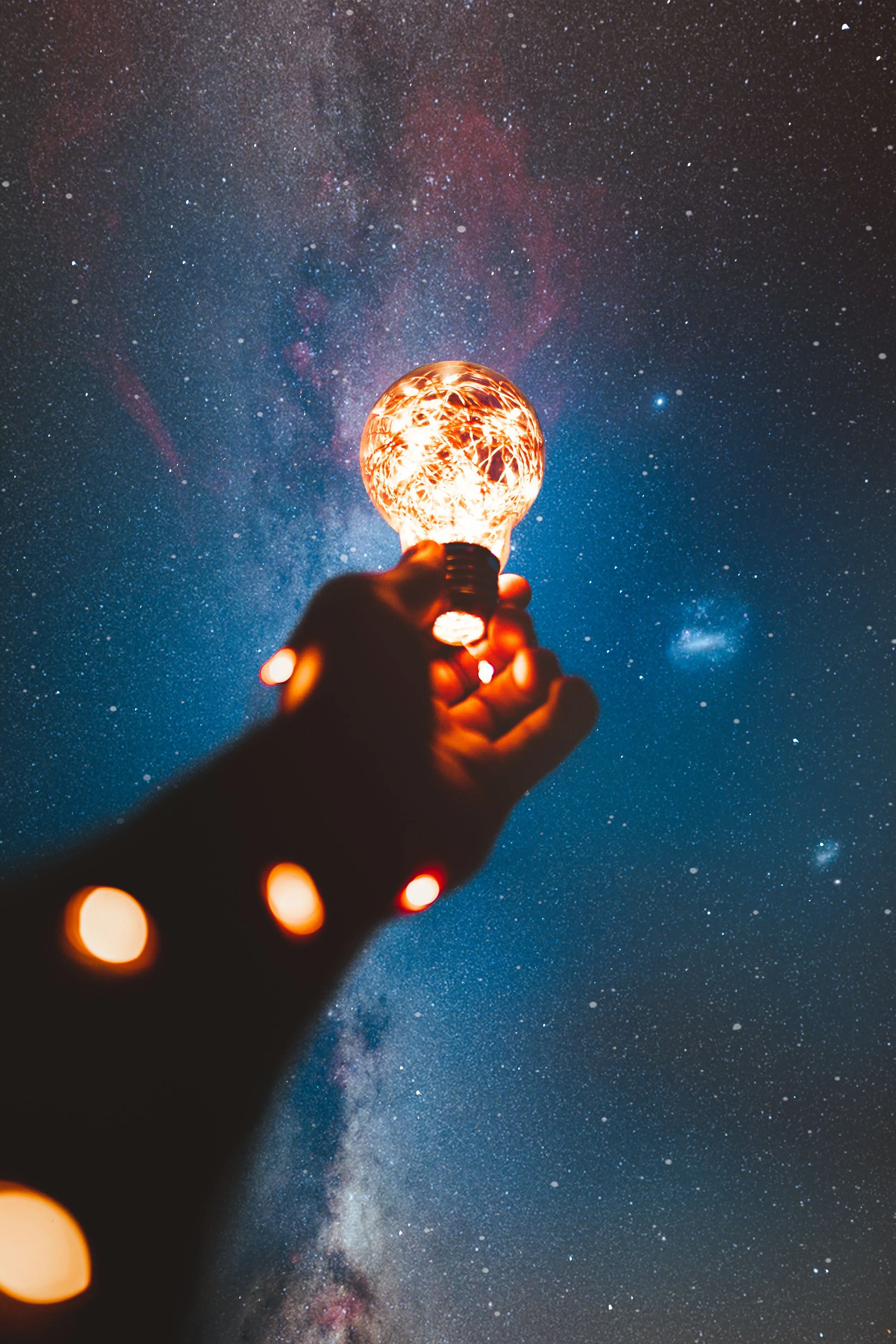 colorful photo, hand holding lightbulb toward a galactic sky, imaginative photography
