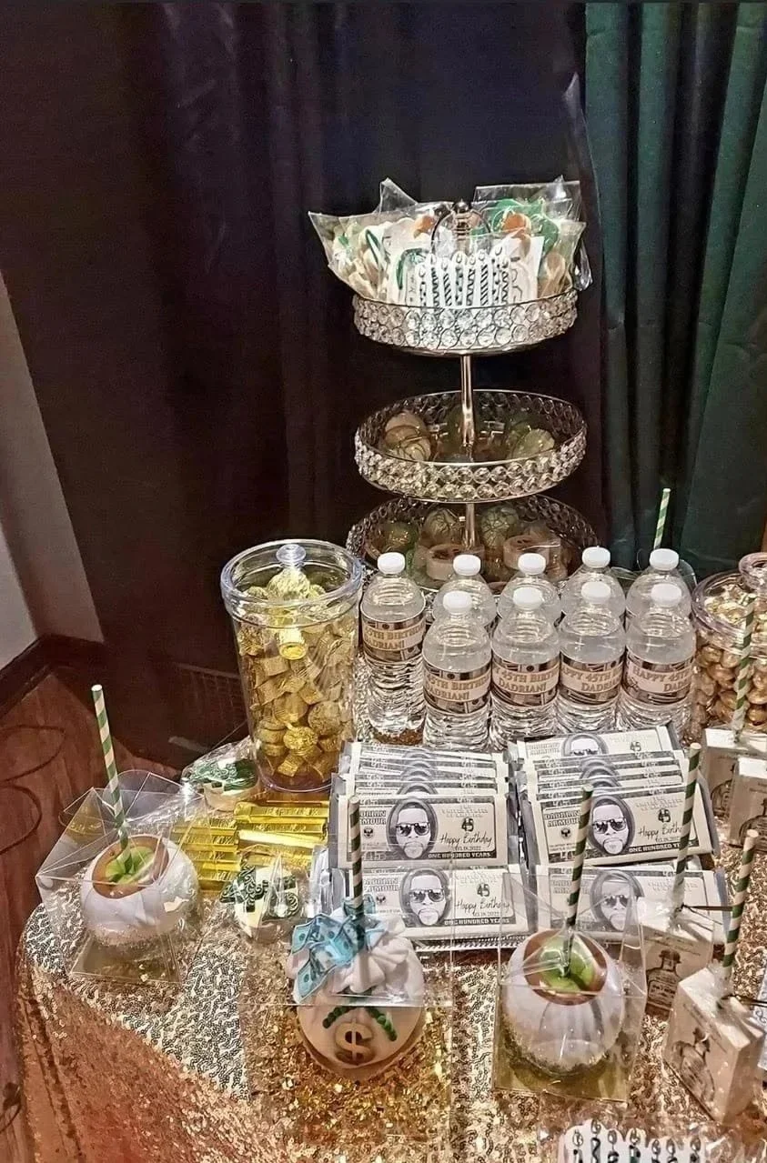 Get Rich or Die Tryin' birthday themed party favor display with custom drinks, water bottles, candy, lollipops, sunglasses, and dollar-sign decorations.