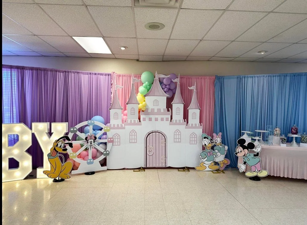 Pink-and-white Disney-themed children's party with a castle backdrop, Mickey and friends, balloons, pastel draping, and a dessert table.
