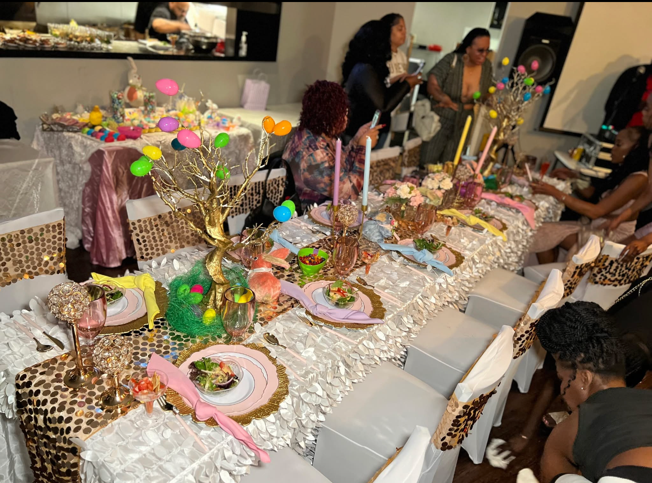 Colorful celebration table with whimsical pastel centerpieces, bright place settings, food, and guests in the background.