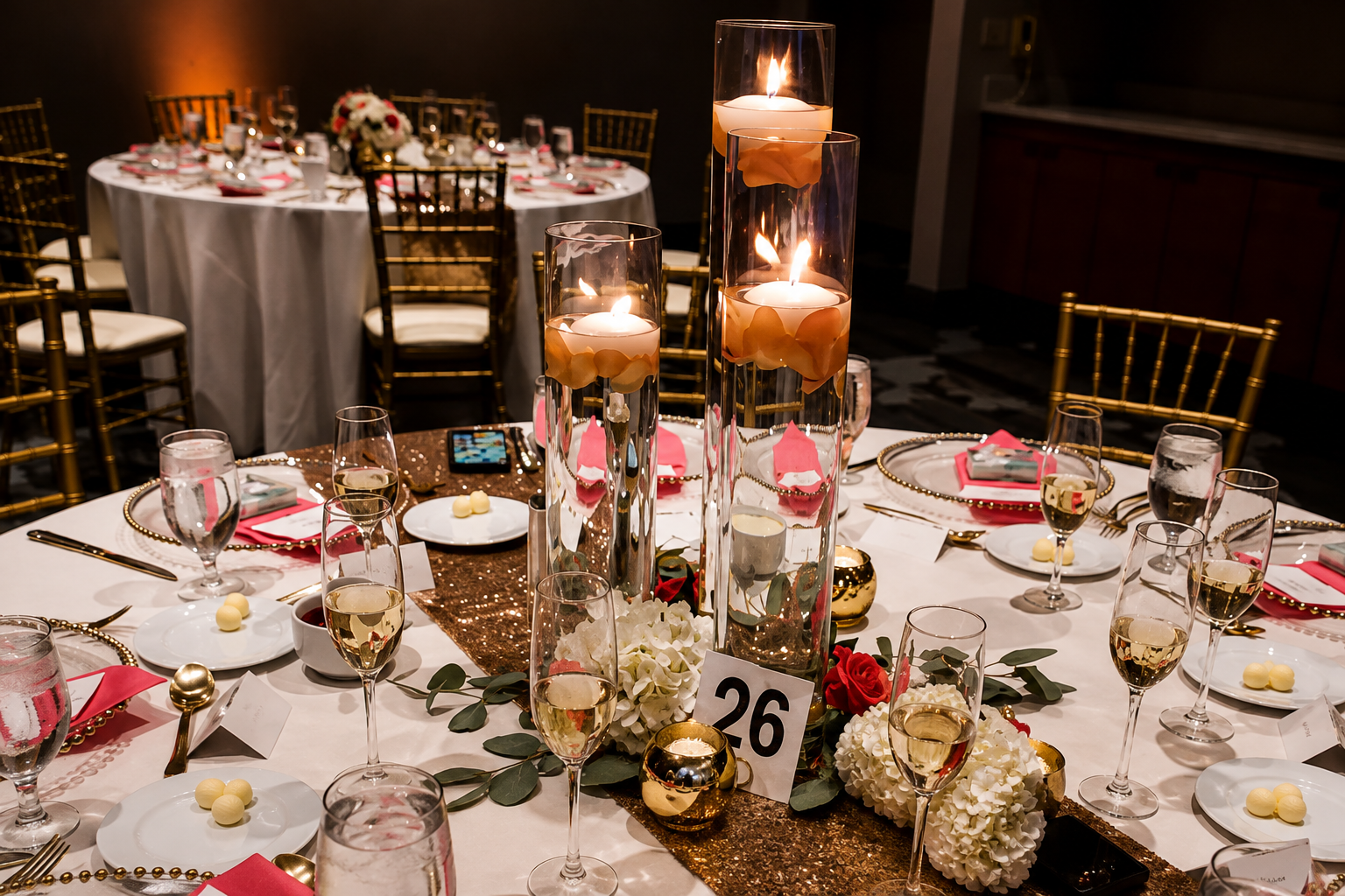 Elegant banquet table set with tall candles, champagne glasses, flower arrangements, and wrapped presents for a formal event.