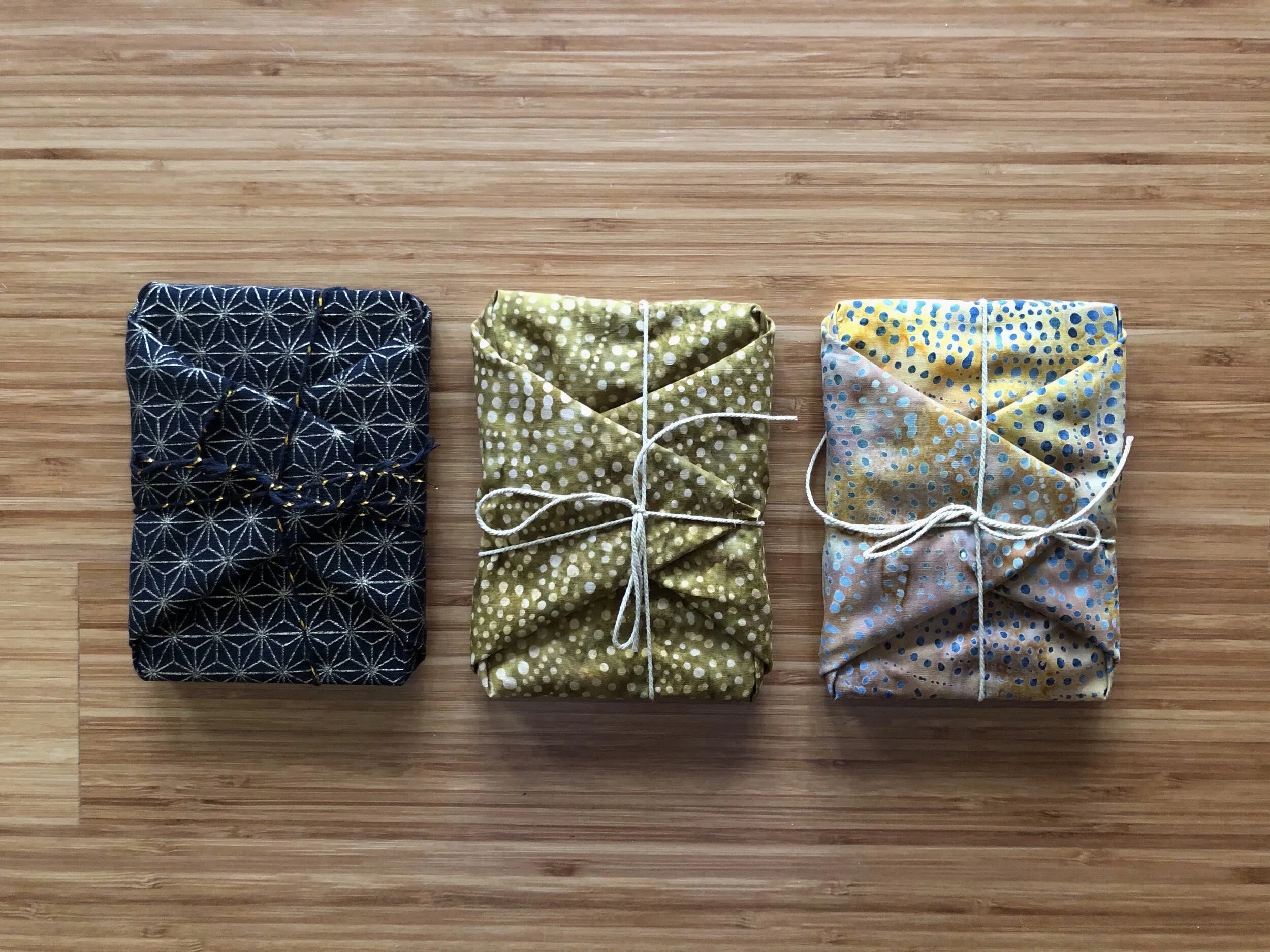 Three decks of cards sit side by side wrapped in differently colored fabric and tied with twine.