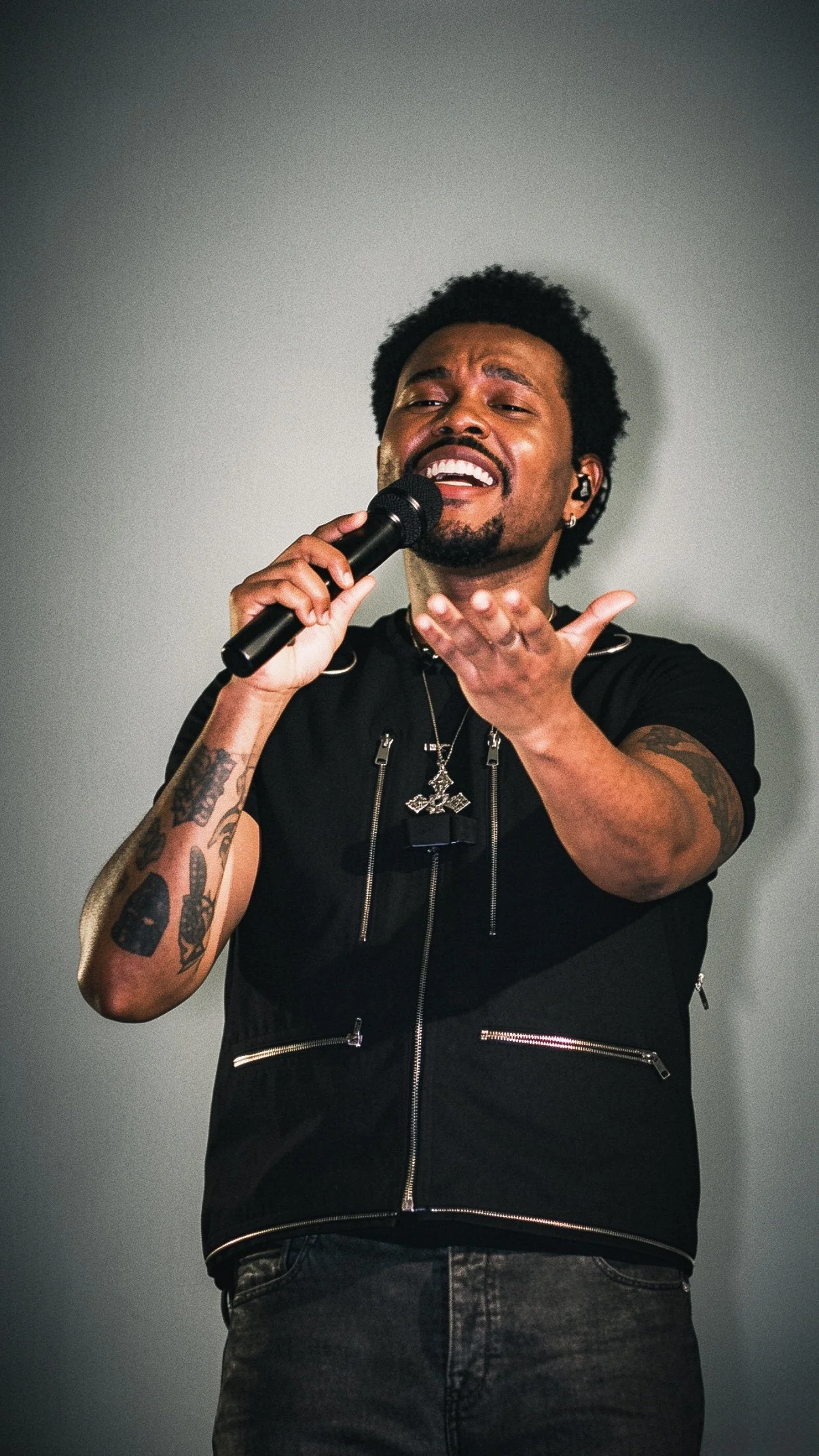 The Weeknd singing into a microphone and reaching toward the audience.