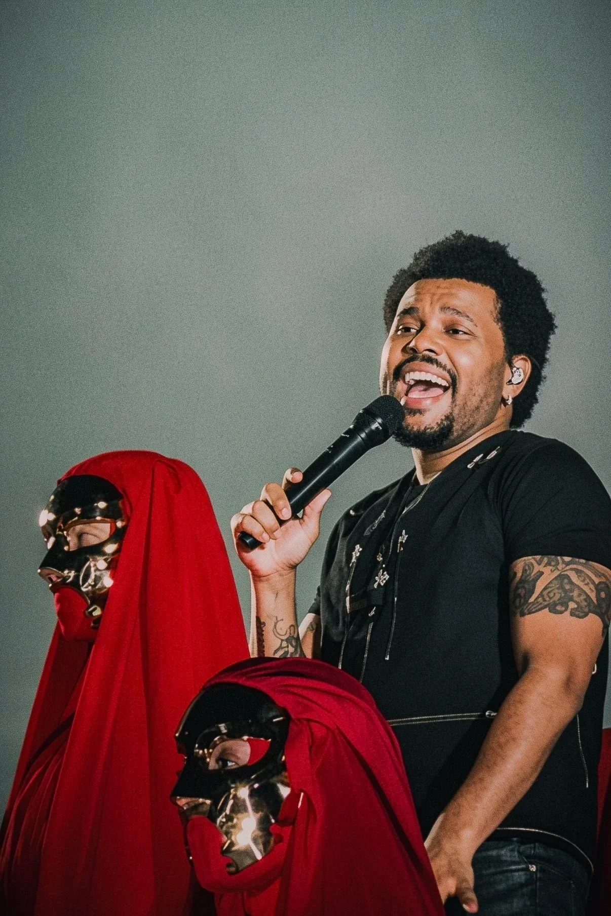 The Weeknd performing beside red-cloaked masked figures during a live concert in Milan.