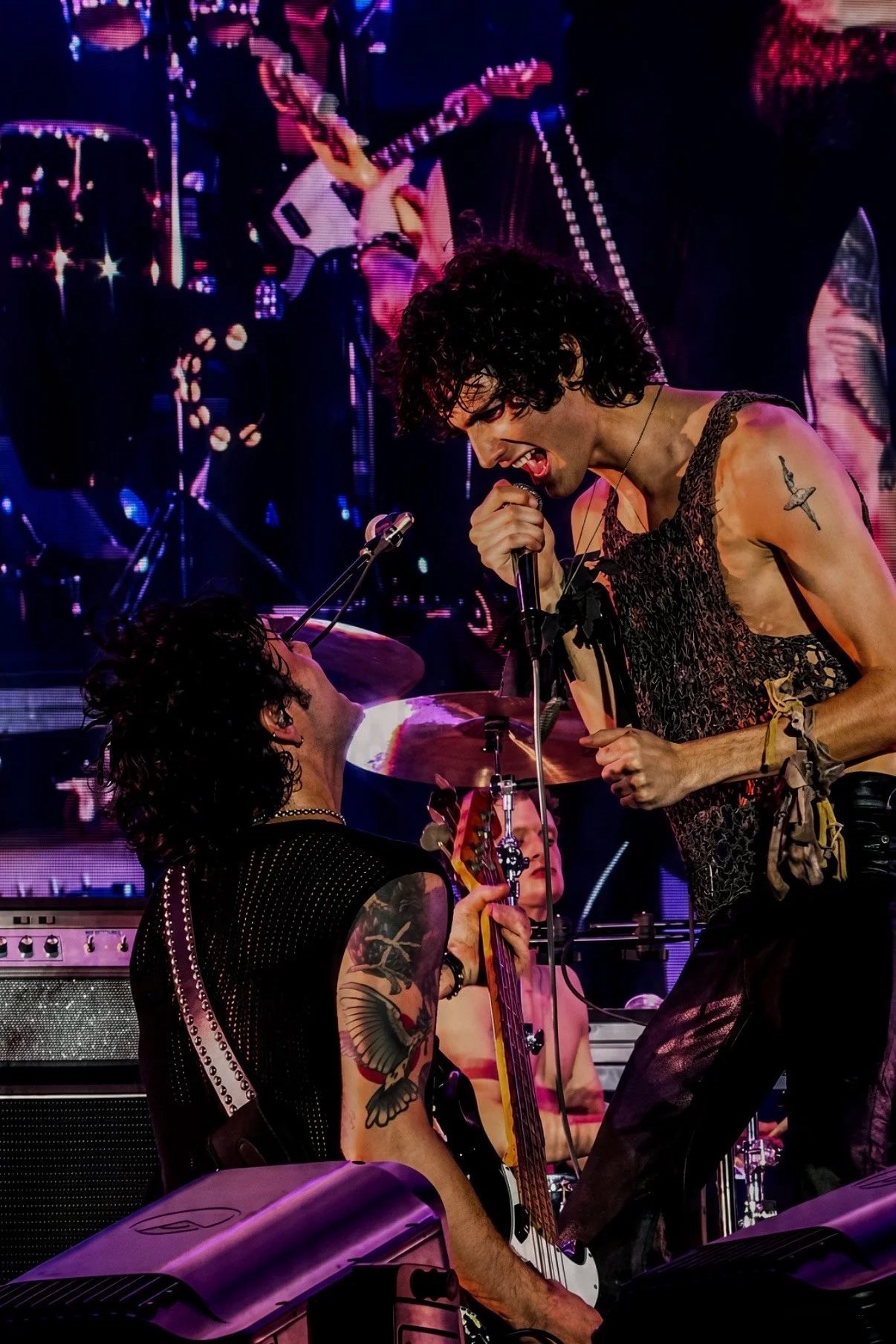 Sombr singing face-to-face with a band member during a live performance.