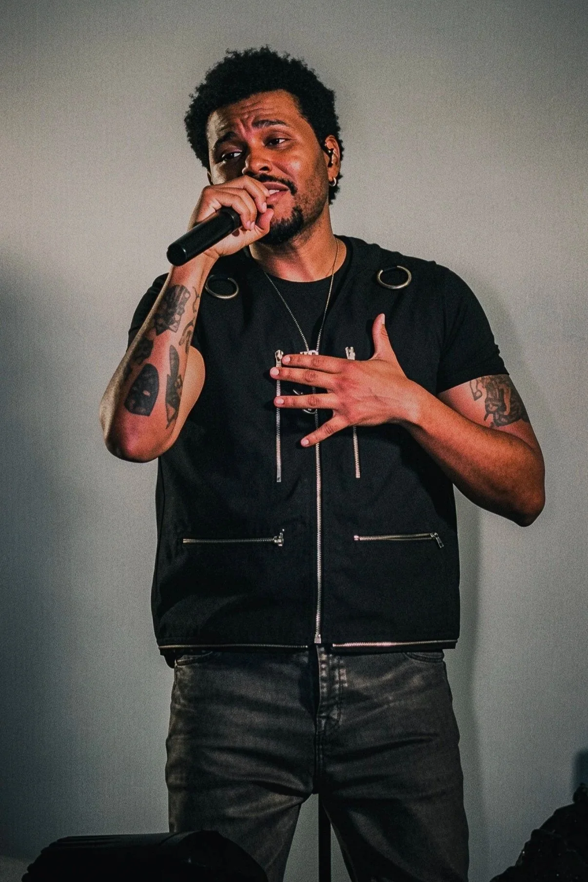 The Weeknd singing with one hand on his chest during a live performance.