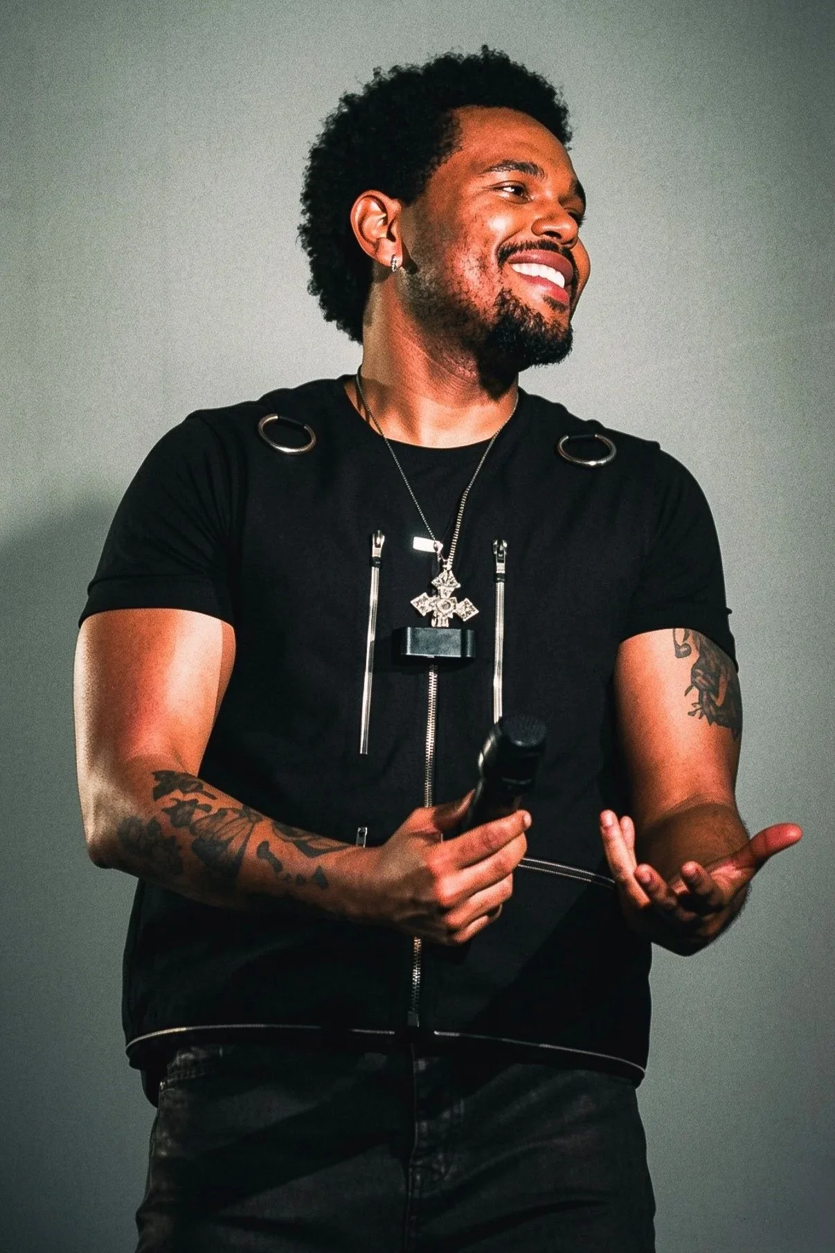 The Weeknd smiling on stage while holding a microphone during a live concert.