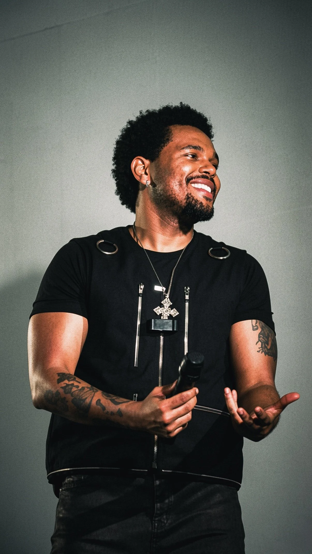 The Weeknd smiling on stage while holding a microphone during a live concert.