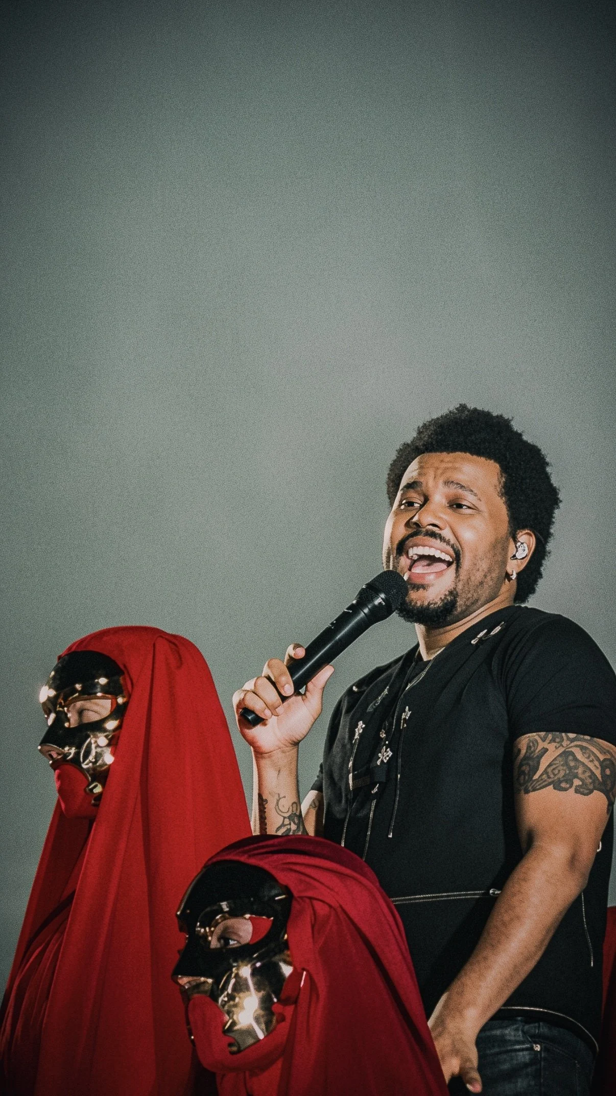 The Weeknd performing beside red-cloaked masked figures during a live concert in Milan.
