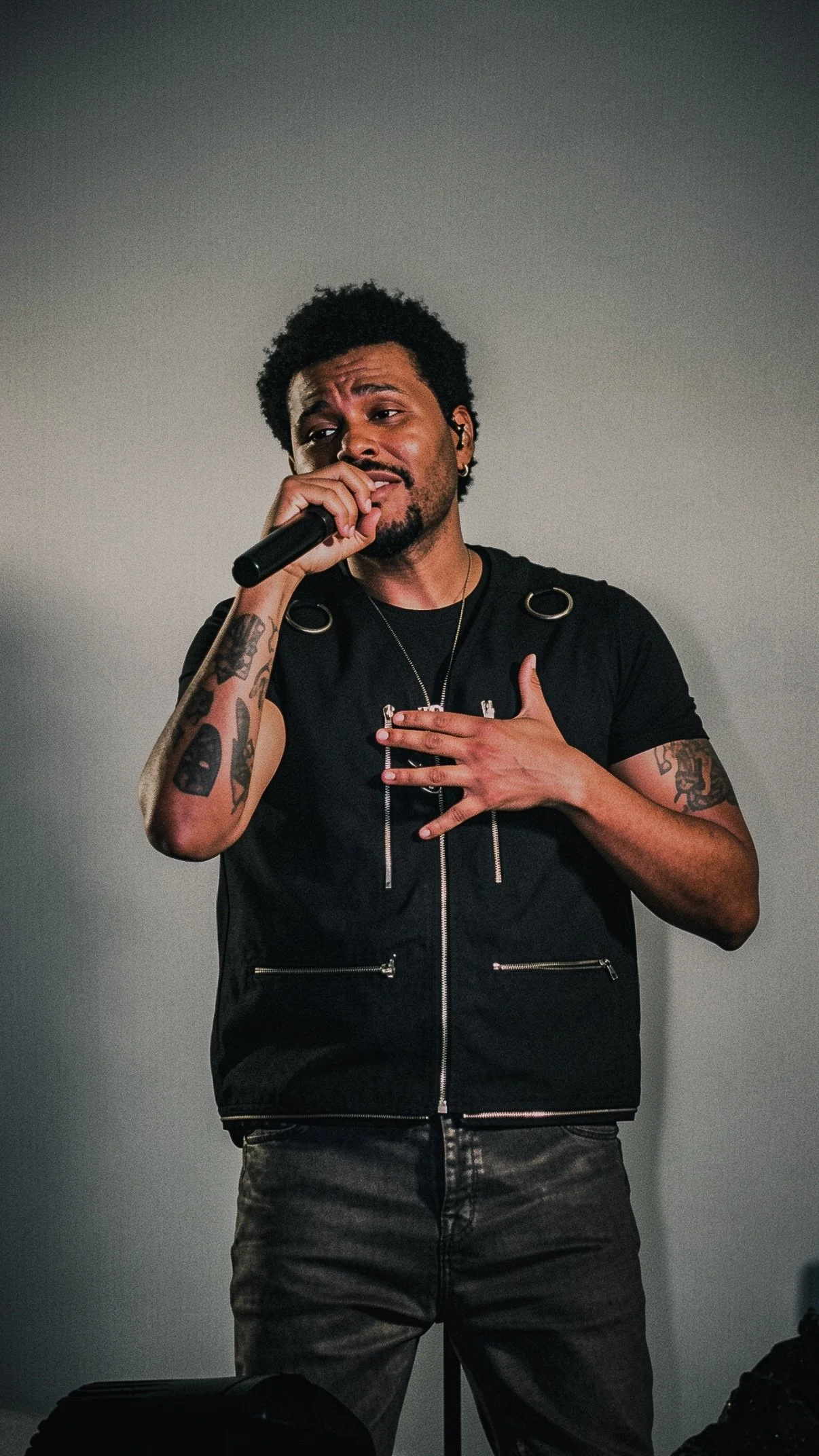 The Weeknd singing with one hand on his chest during a live performance.