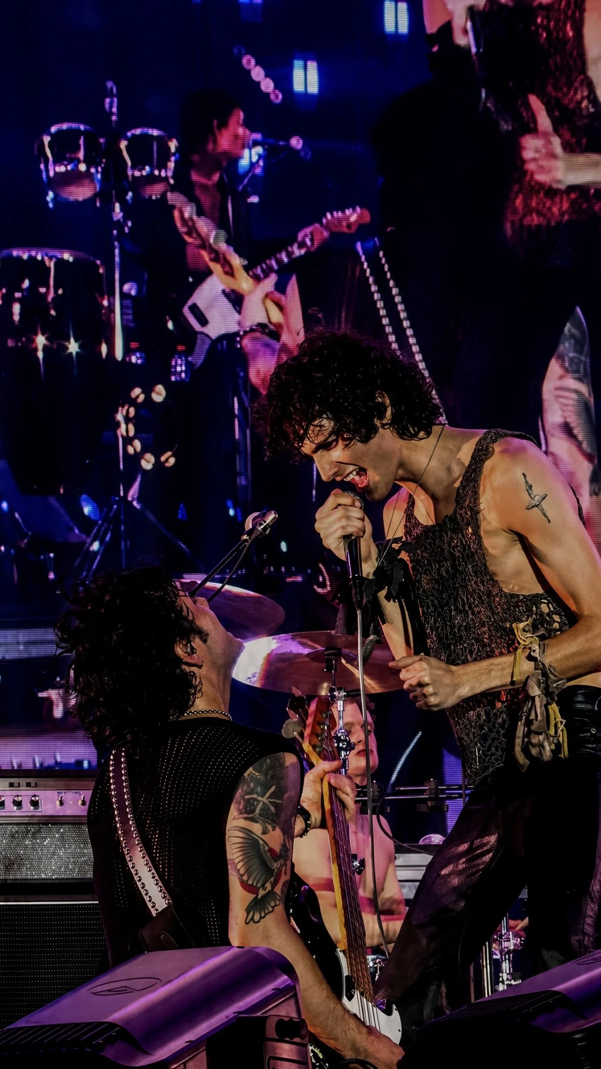 Sombr singing face-to-face with a band member during a live performance.