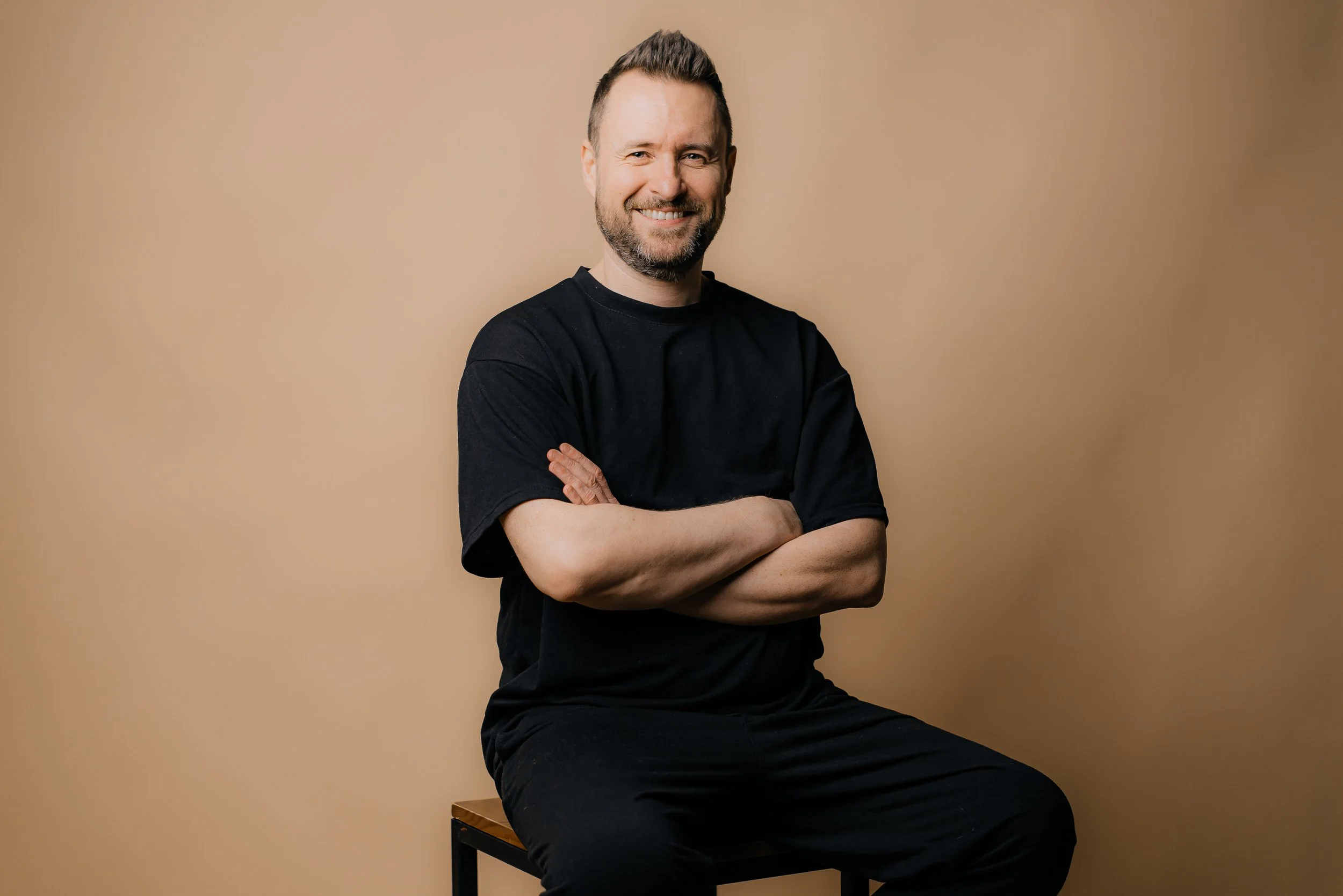 man-smiling-with-arms-crossed-on-beige-backdrop-2026-01-07-00-31-42-utc.jpg