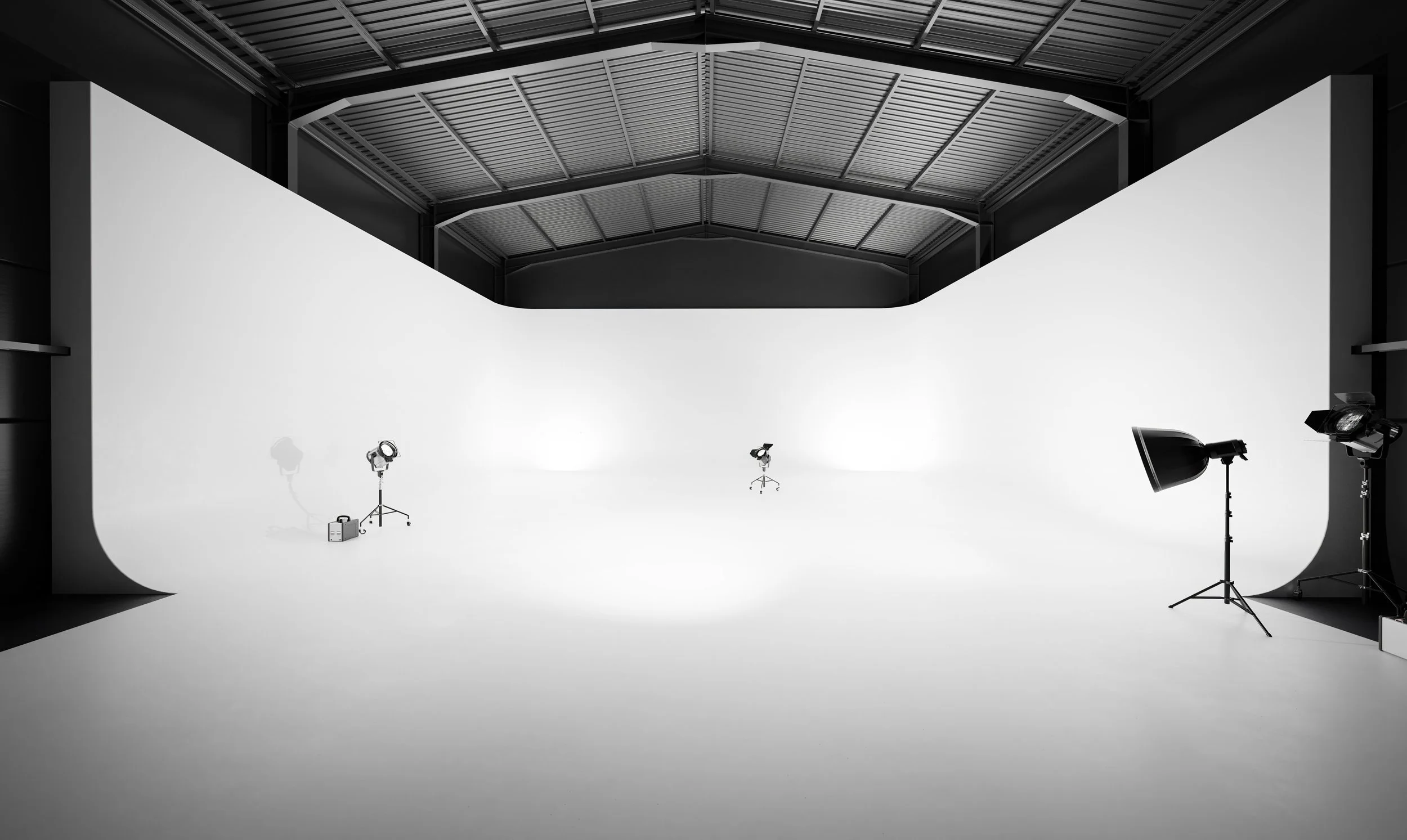A photography studio with a white cyclorama background and studio lights on tripods.