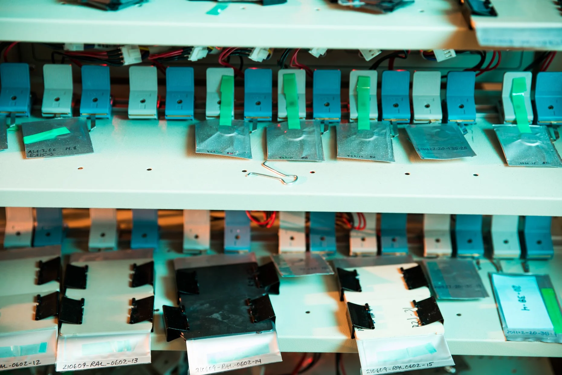 A close-up view of an electronic device's internal components, including multiple small circuit boards with wires and connectors, organized on a white rack or internal frame.