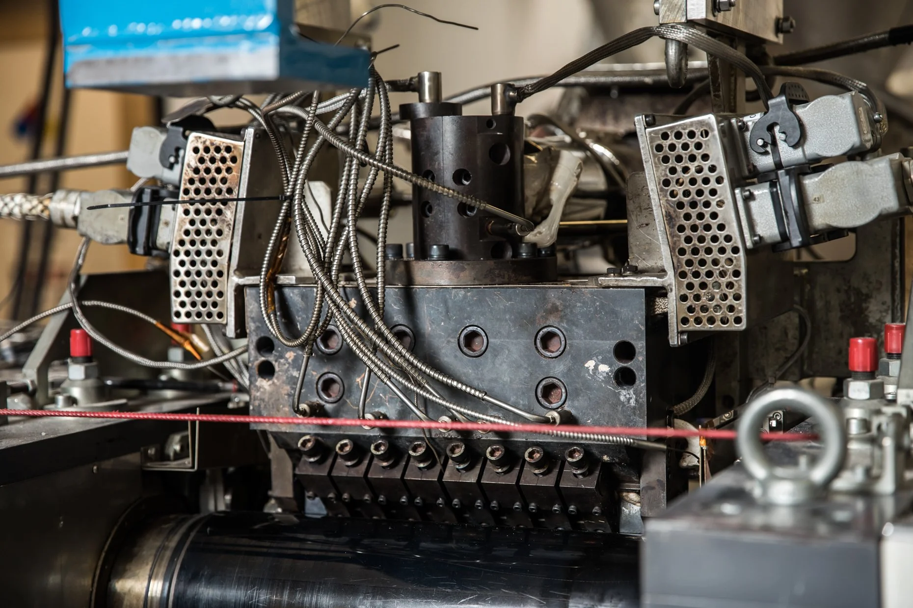 Close-up of complex mechanical and electronic components with metal wires, circuit boards, and metal gears mounted on a black metal framework.