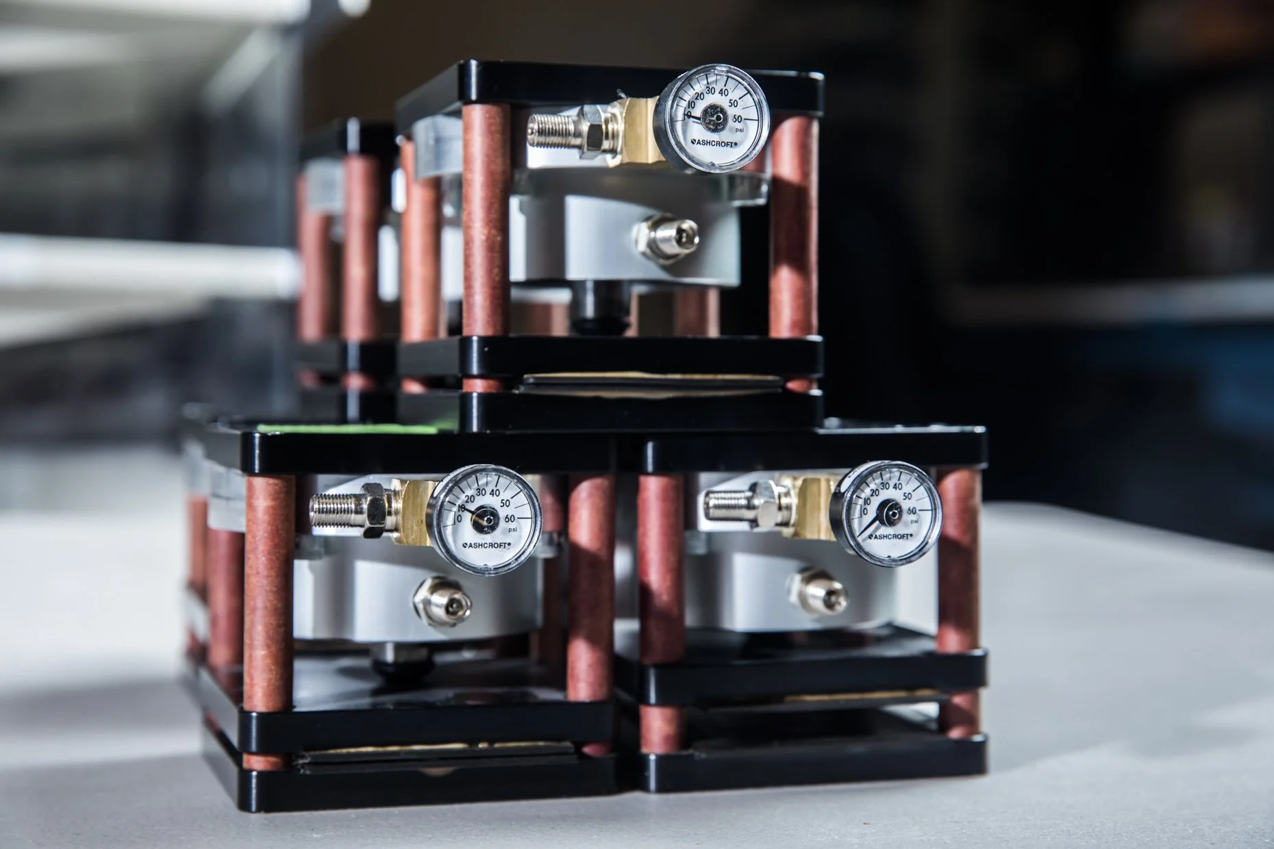 Close-up of a mechanical device with multiple pressure gauges, copper pipes, and metal components arranged in a layered structure.