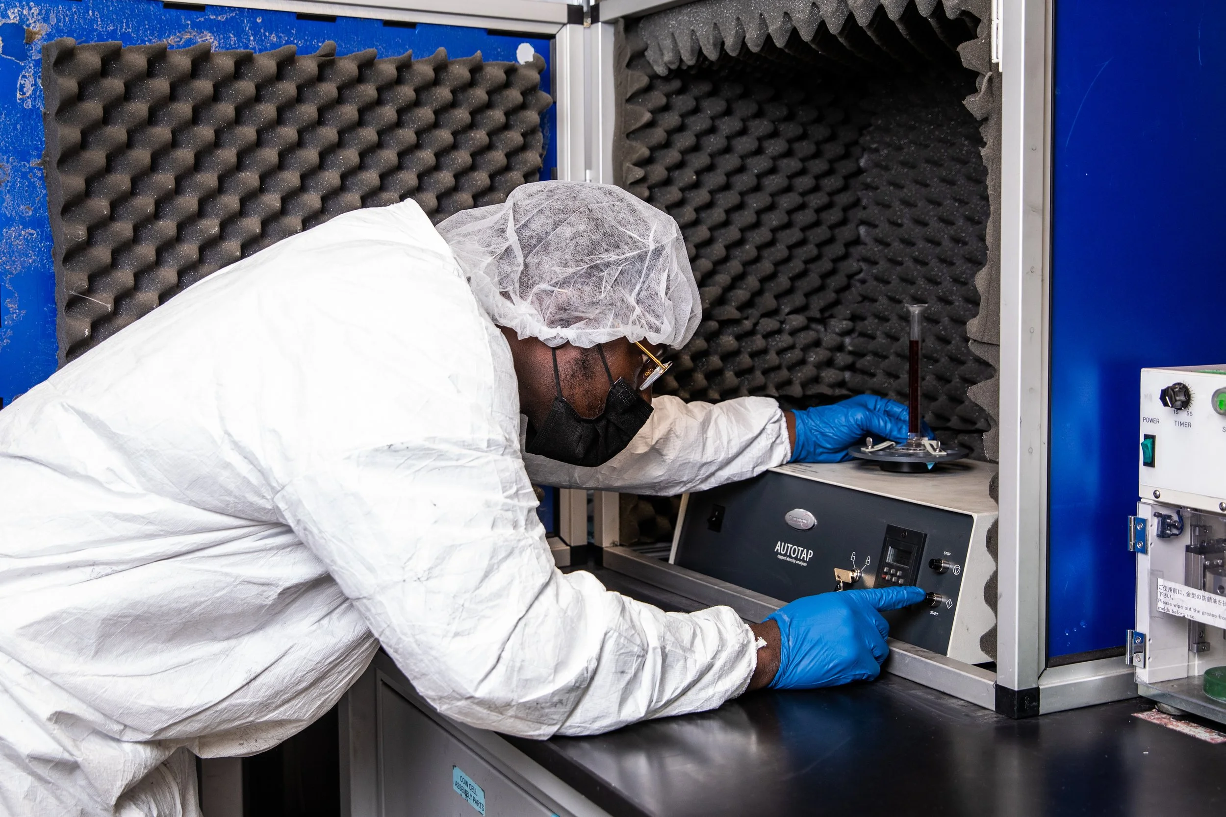 A scientist in protective gear working with scientific equipment in a laboratory environment.
