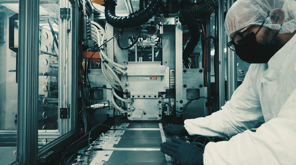 Scientist working with advanced machinery in a clean lab environment, wearing protective gear.