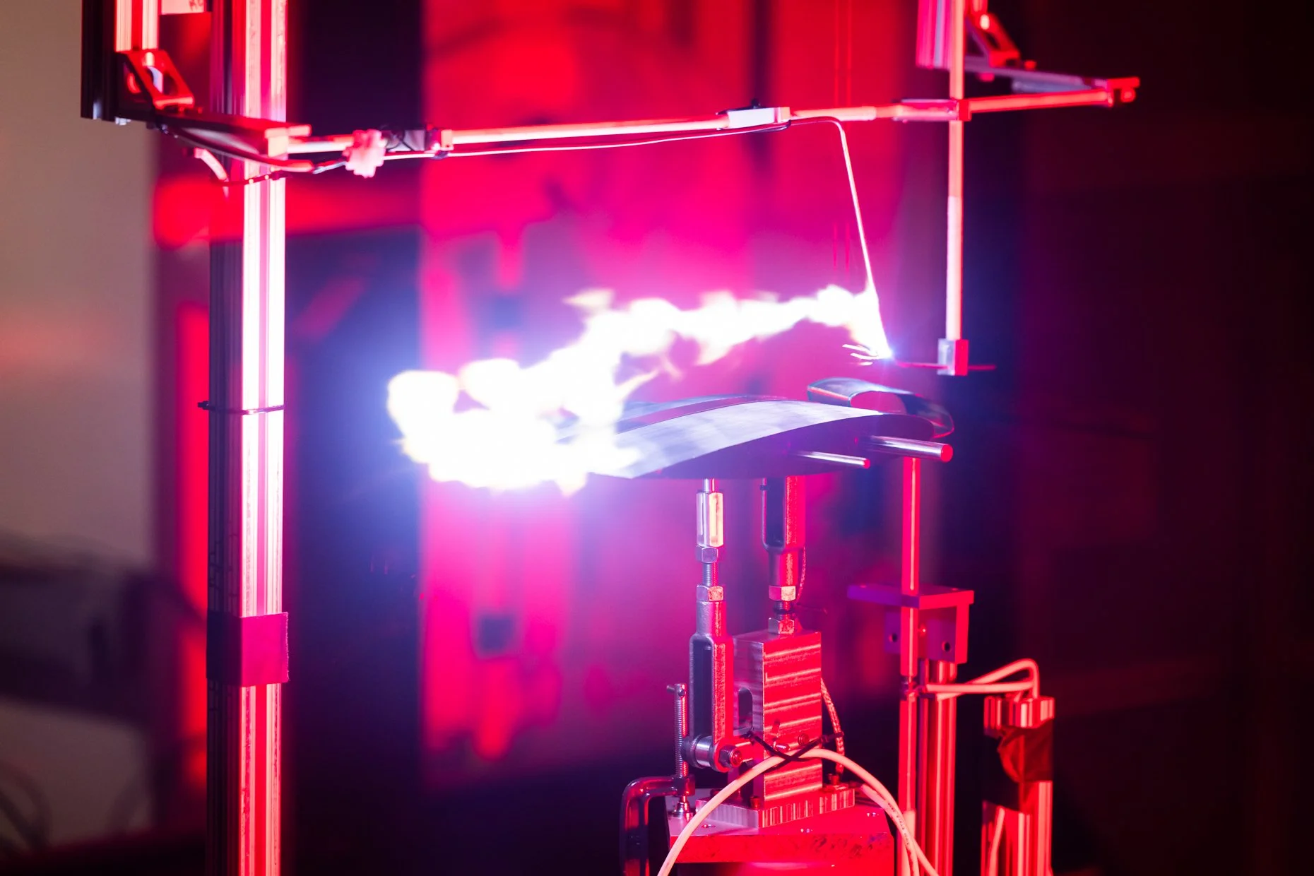 A scientific demonstration with electrical arcs and red neon lights in a laboratory setup.