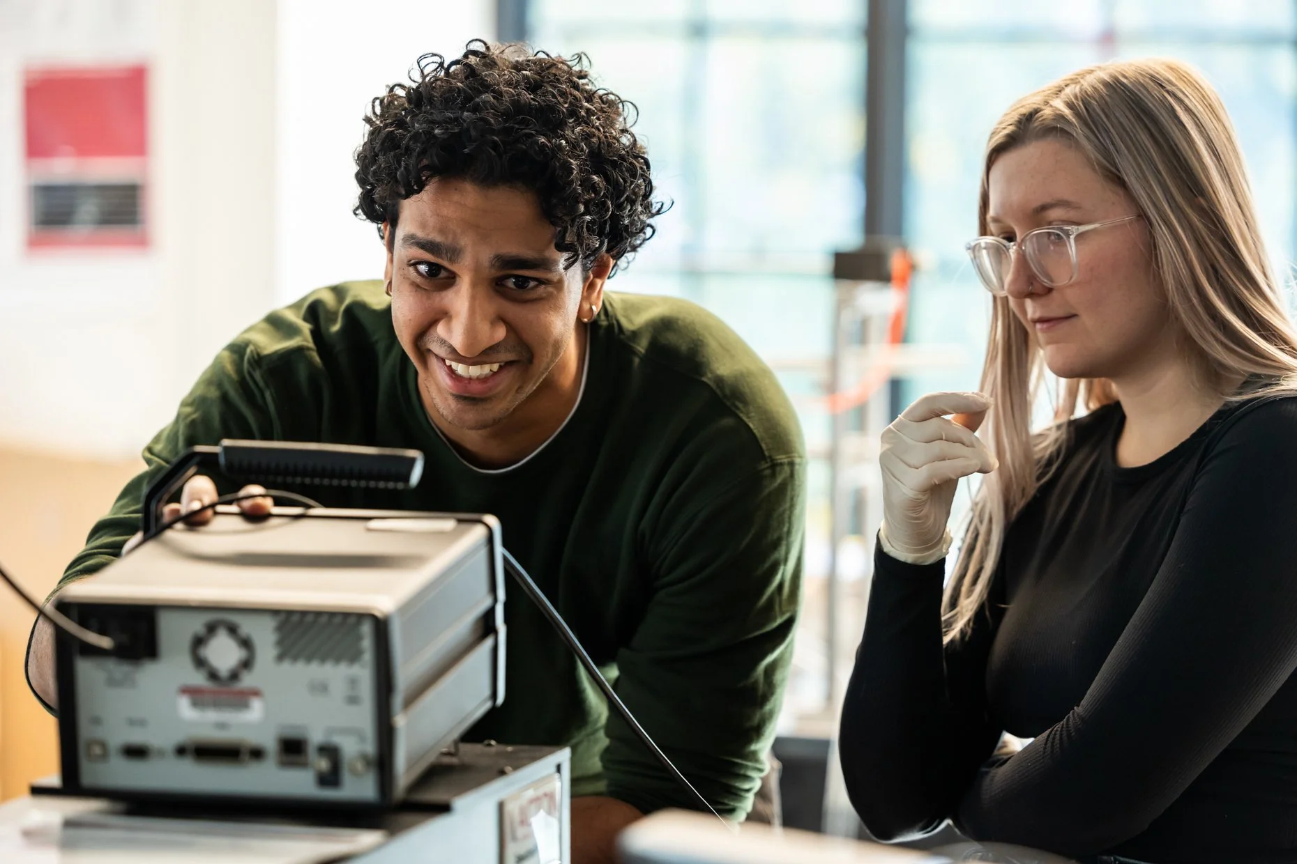 Two young women working together on a technical project with electronic equipment in a bright modern space.