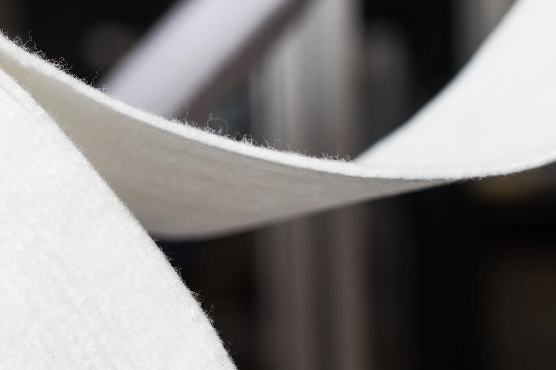 Close-up of a piece of white fabric or paper with a blurred dark and gray background.