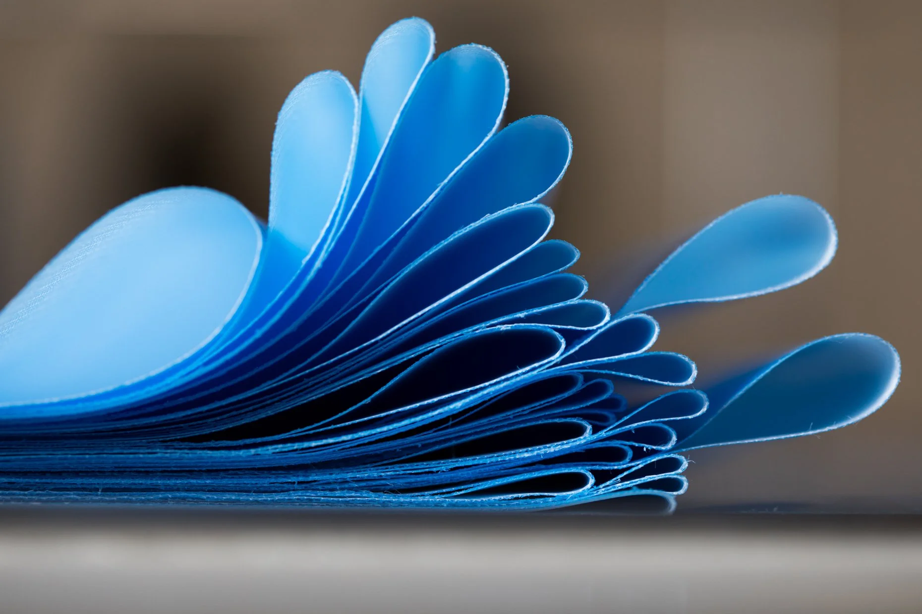 Close-up of blue pages of a notebook or a book, fanned out and curling at the edges.