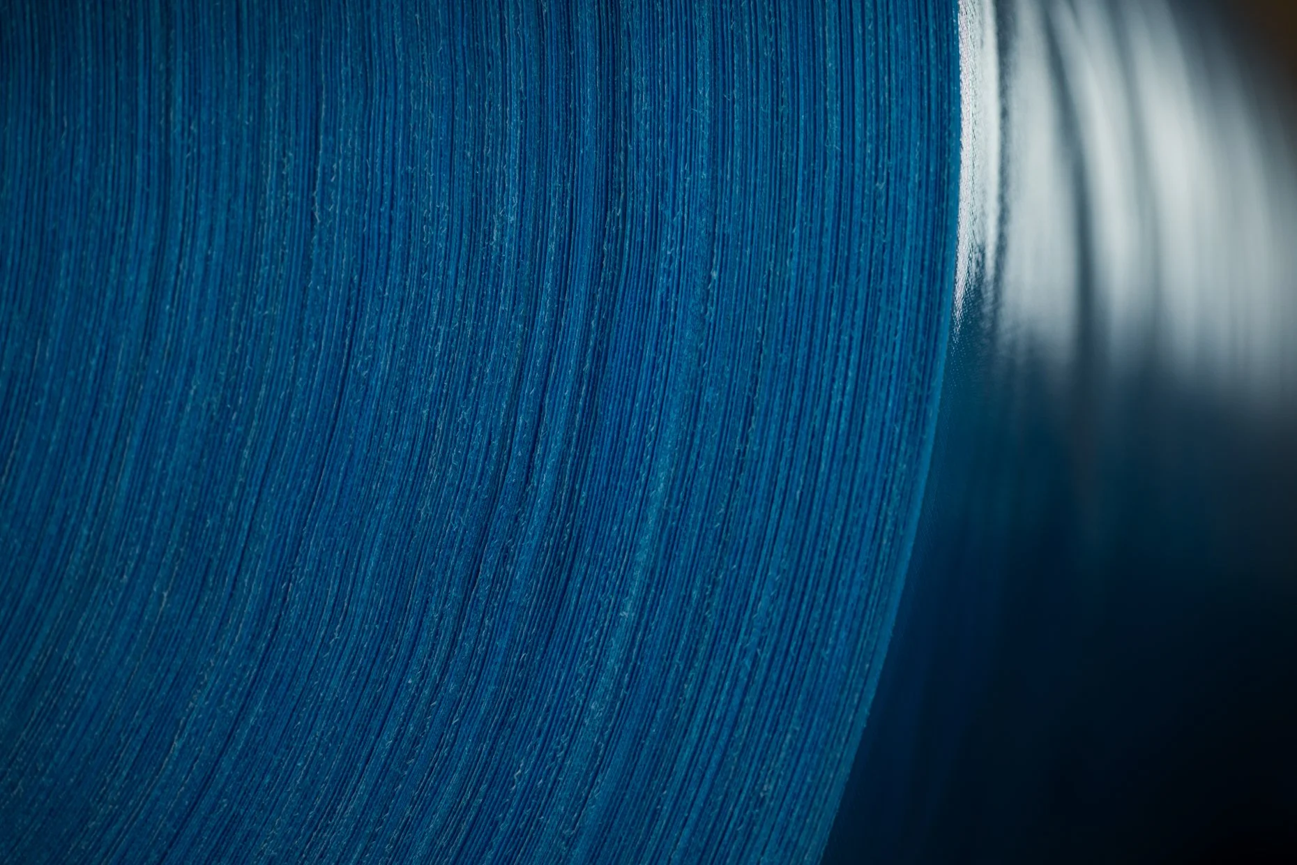 Close-up of a blue textured material, possibly paper or fabric, with a curved edge and soft lighting.
