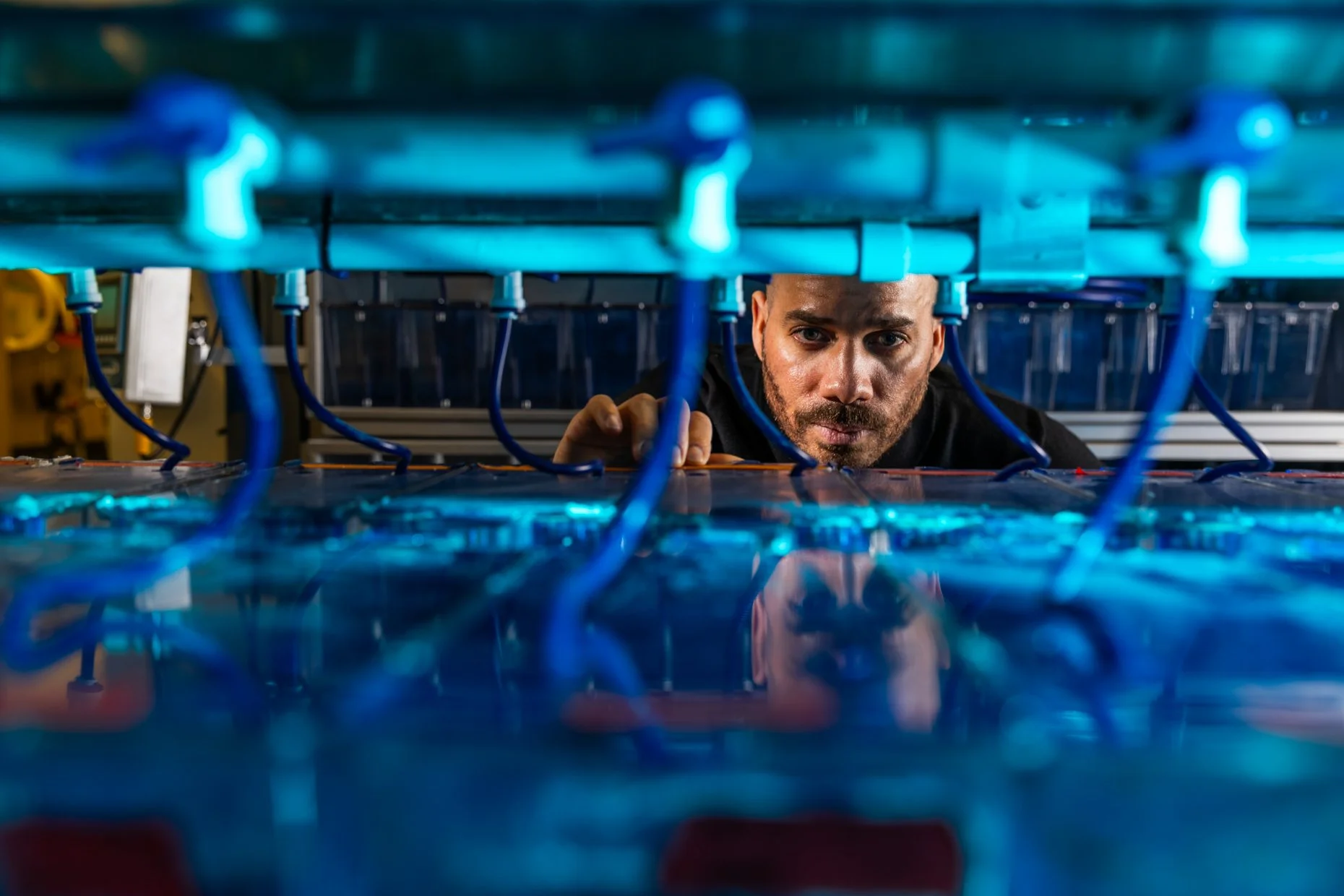 A person working on electronic circuit boards with blue wiring, under blue lighting.