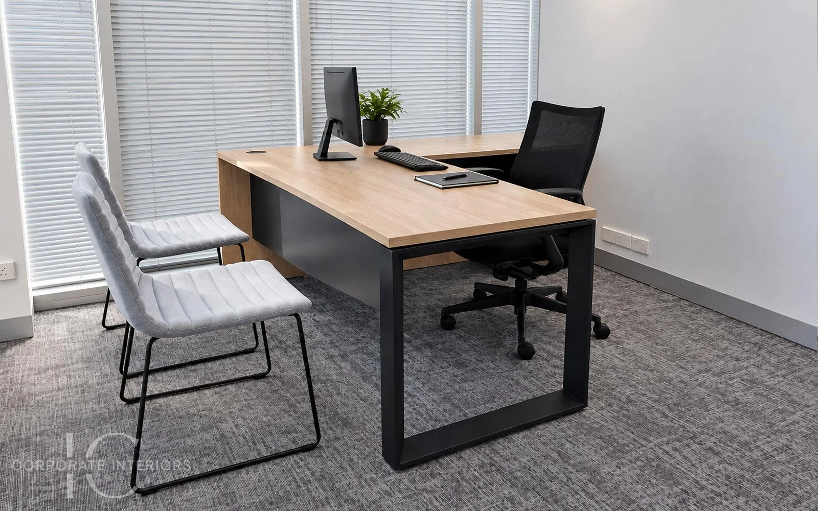 Timber executive desk with black feature frame, black mesh office chair and two grey upholstered visitor chairs.