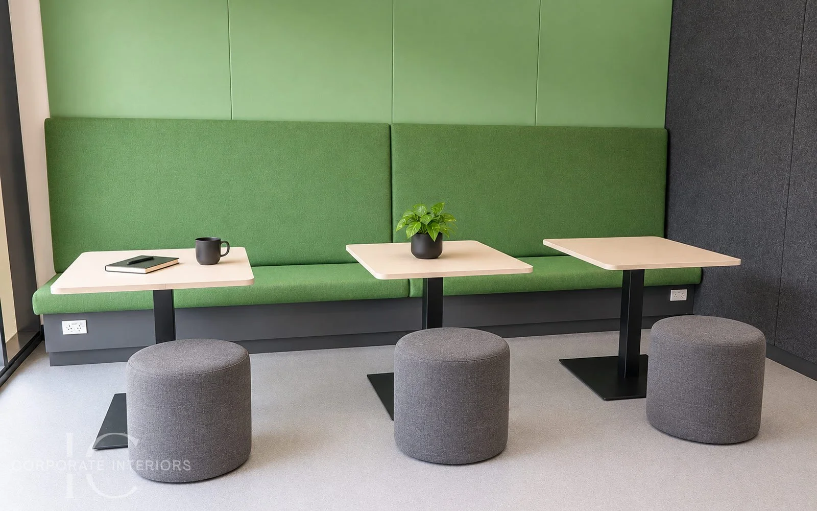 Staff breakout area with upholstered bench seating, café tables and grey ottomans.