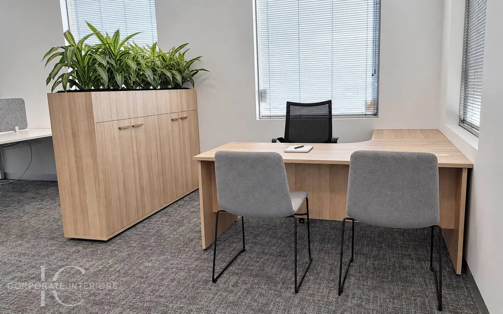 Timber executive desk with grey fabric visitor chairs and matching custom timber storage unit with integrated planter.