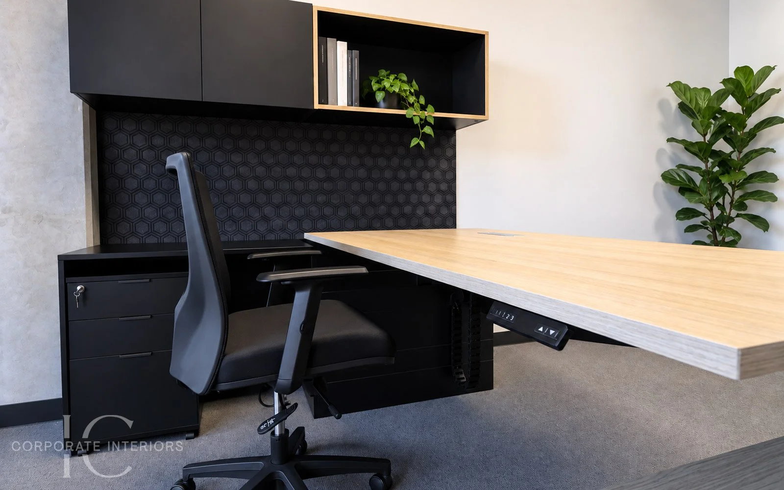 Height adjustable timber office desk with custom overhead storage and black feature pinboard.