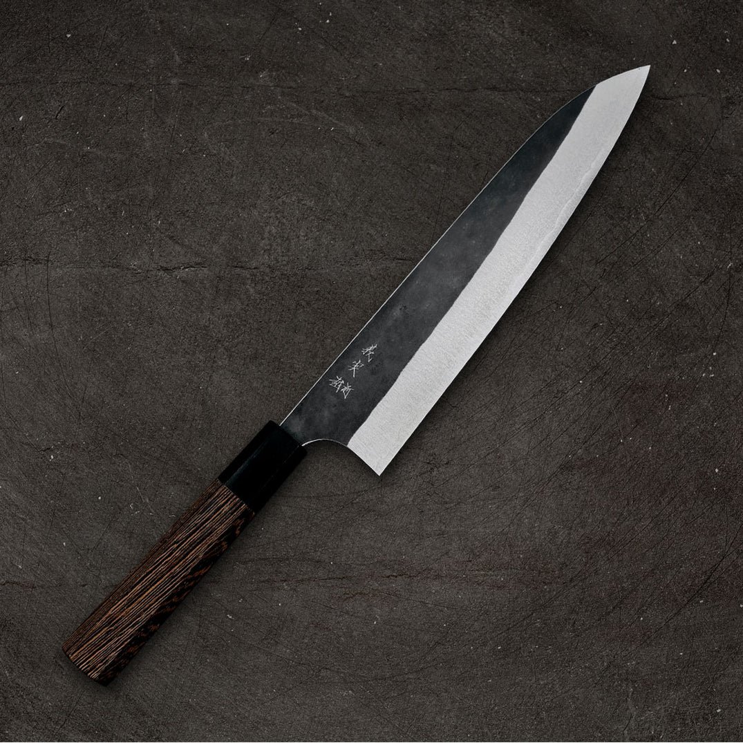 Een Japans koksmes met een donker houten handvat op een houten snijplank.