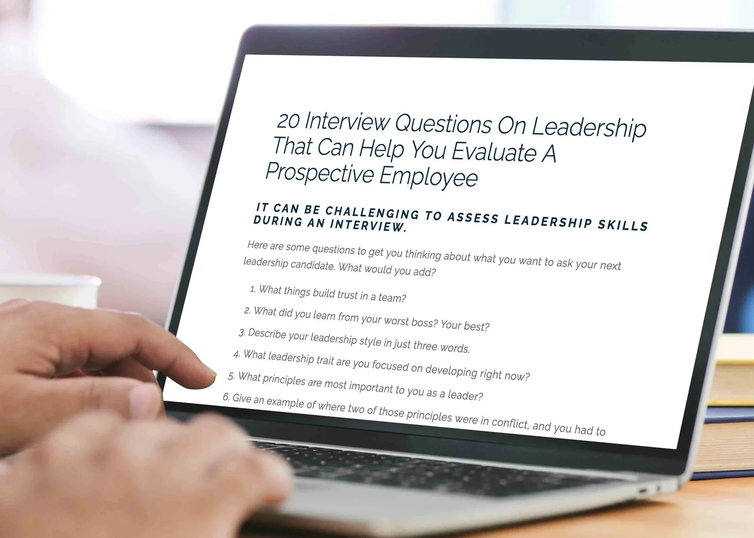 20 interview questions on leadership on laptop computer as hands type